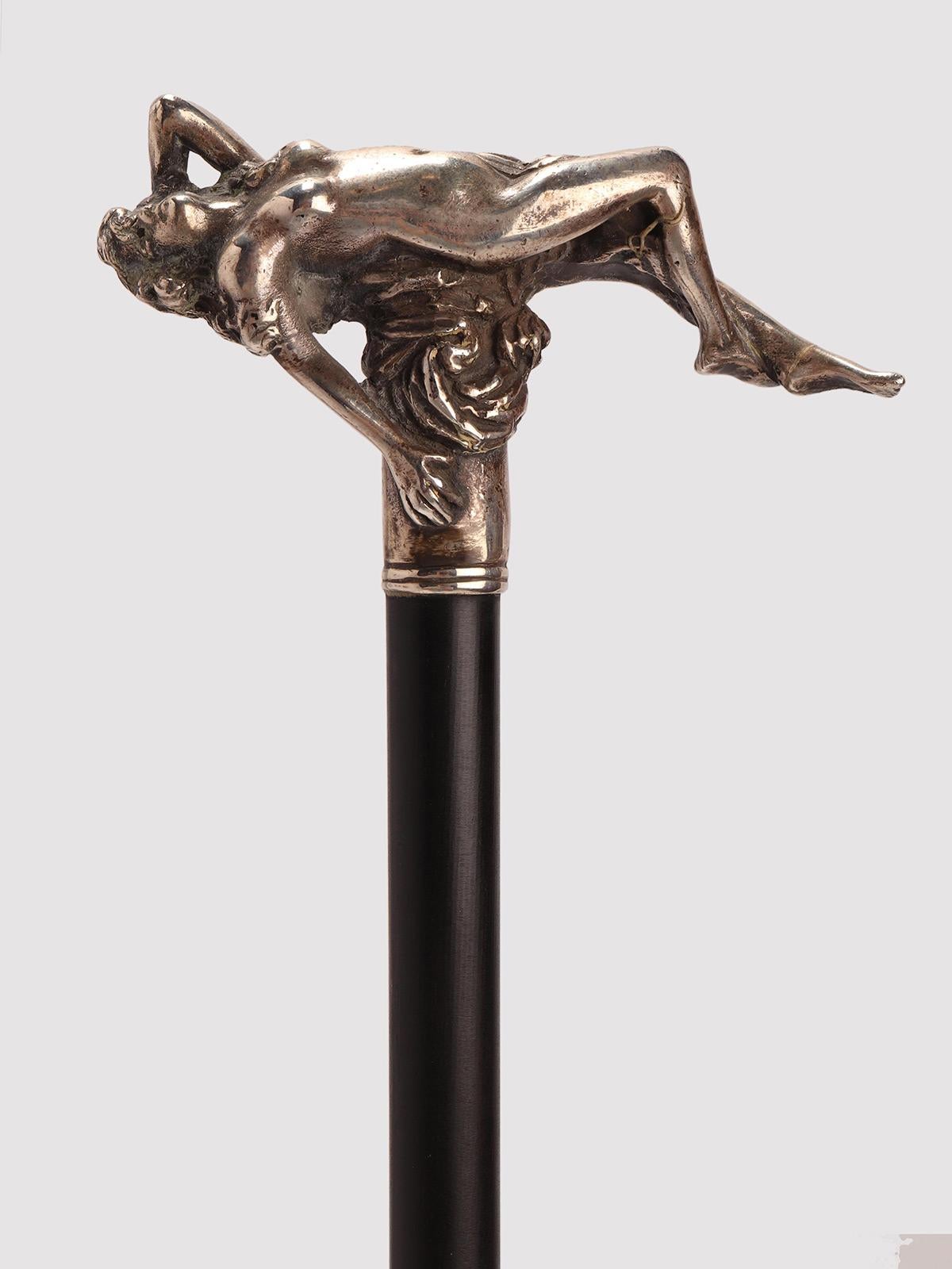 Spazierstock: Liberty-Knauf aus 800/1000 Silber. Der Knauf zeigt die Figur einer liegenden, nackten Frau im Rund. Schaft aus massivem Ebenholz. Metallspitze. Deutschland um 1900.