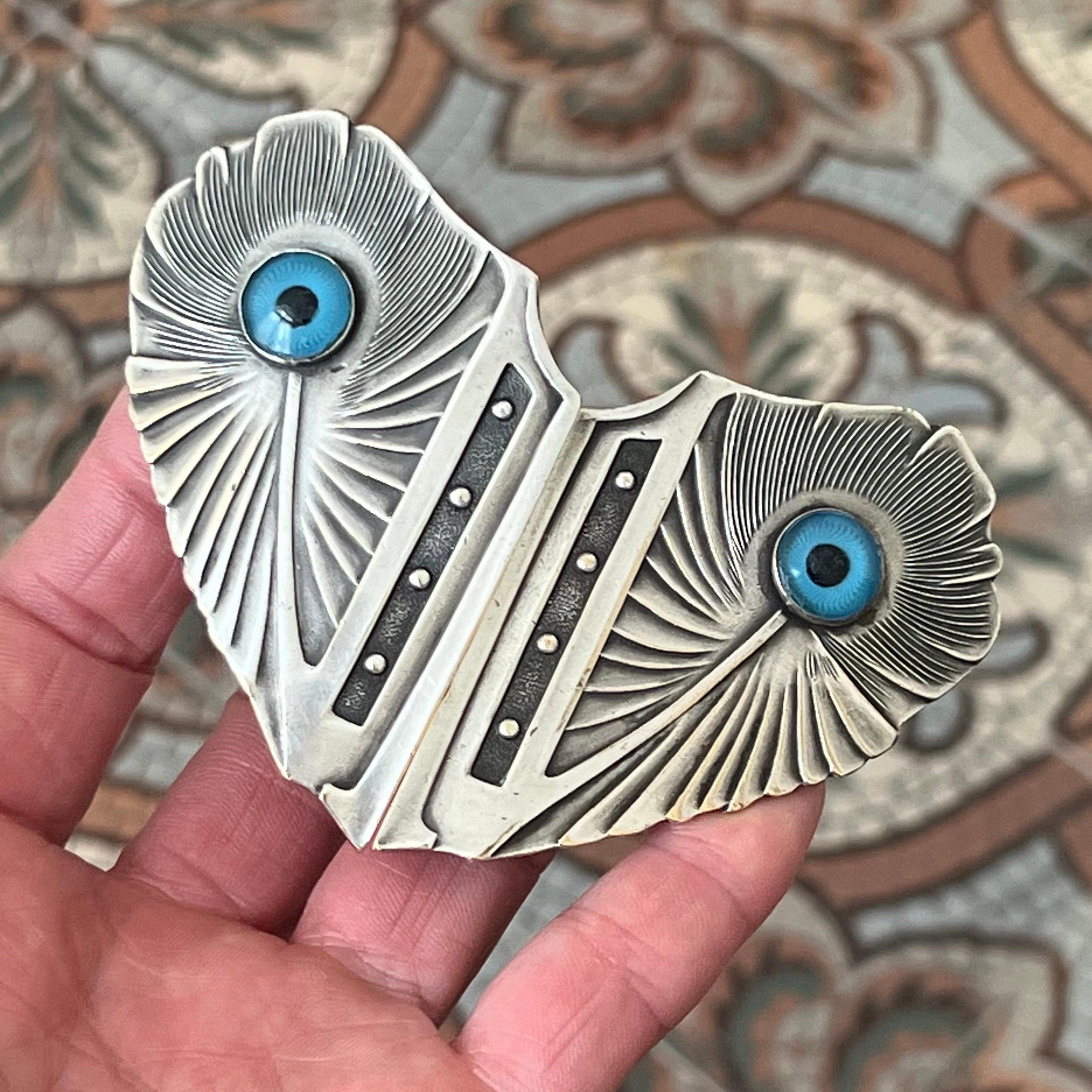 An elegant and beautifully crafted Art Nouveau belt buckle, designed as a pair of stylized peacock feathers, dating to around 1900.

The buckle is composed of two separate halves which interlock to form a symmetrical, fan-like composition. Each half