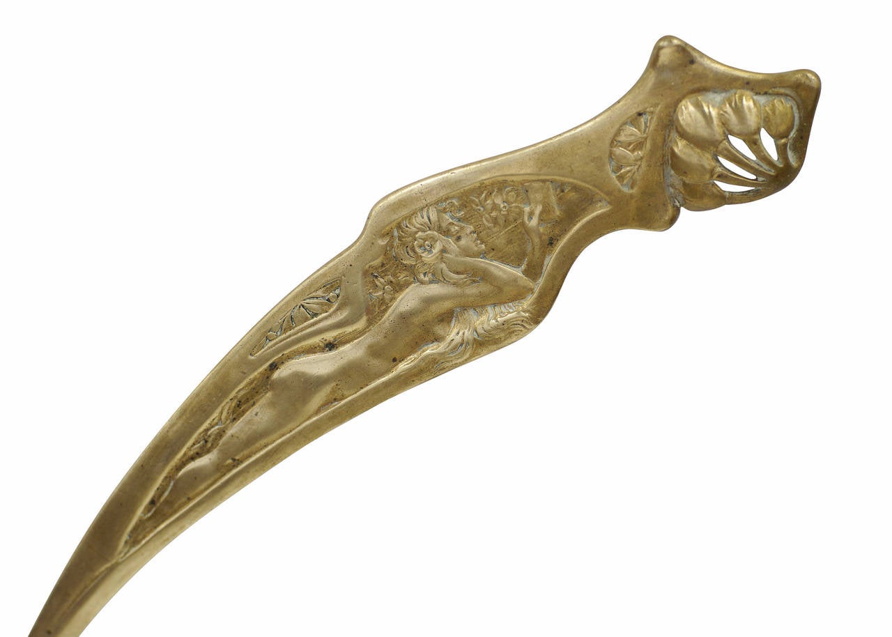 This piece is a solid bronze letter opener with Art Nouveau designs along the front and unique curved blade. The handle features a relief of a nude woman holding a book in great detail, circa 1900.