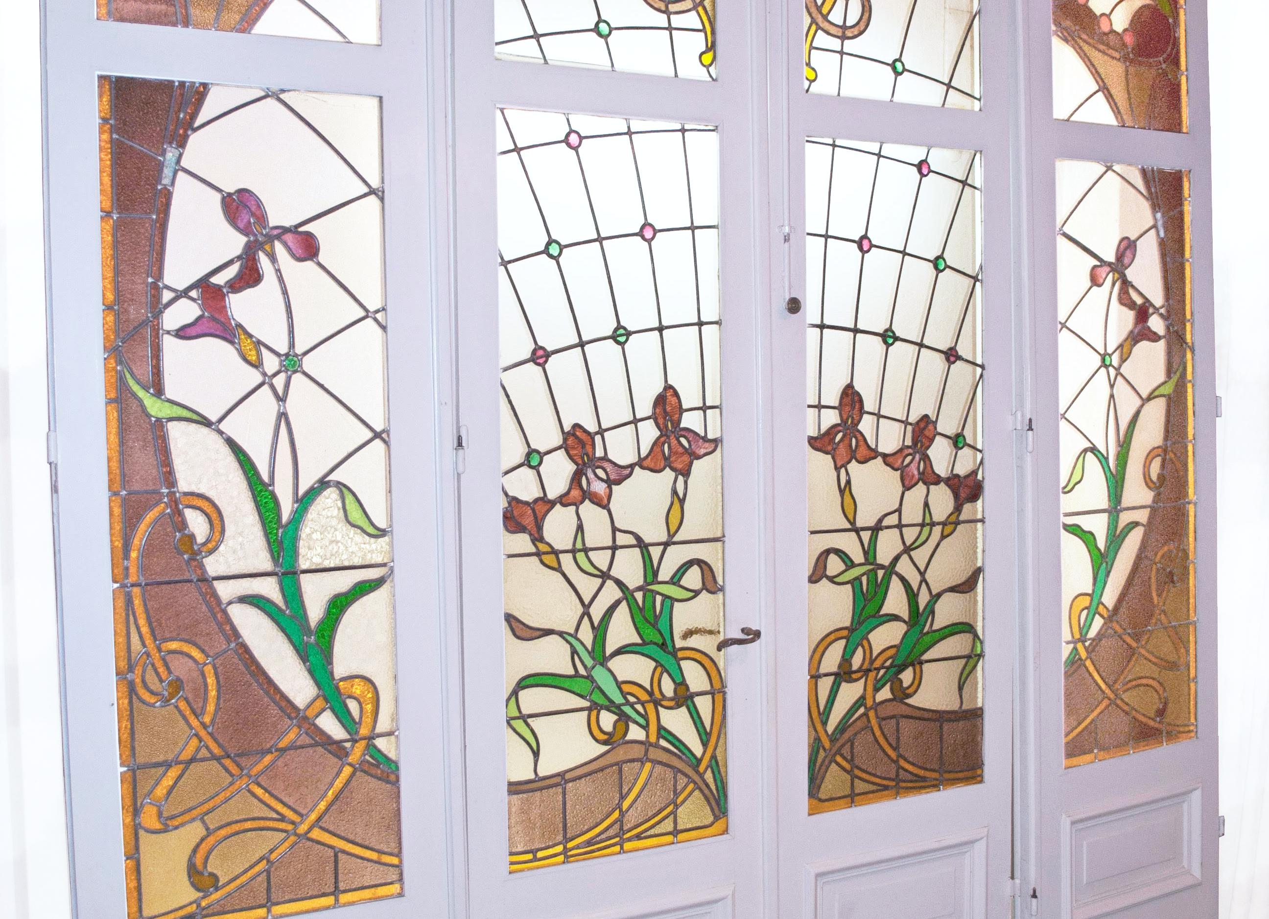 A wonderful set of eight French stained glass windows in four doors with bronze handles. The set of eight panels is in stained glass in polychrome glass with shutters, locks, handle and original key.  

Beautiful stained glass from the Art Nouveau