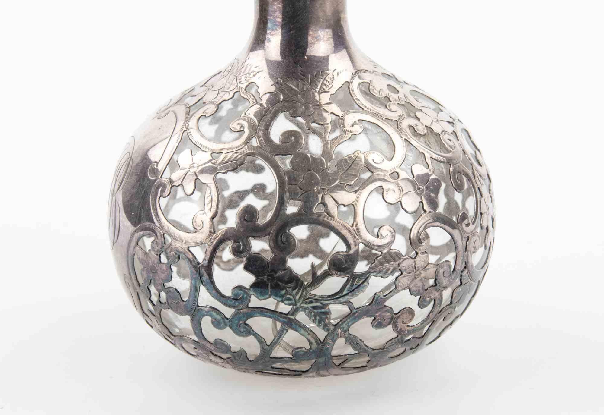 Art Nouveau Sterling Overlay Glass Bottle realized in the early years of 20th Century.

Repairs on the glass structure, otherwise very good condition.