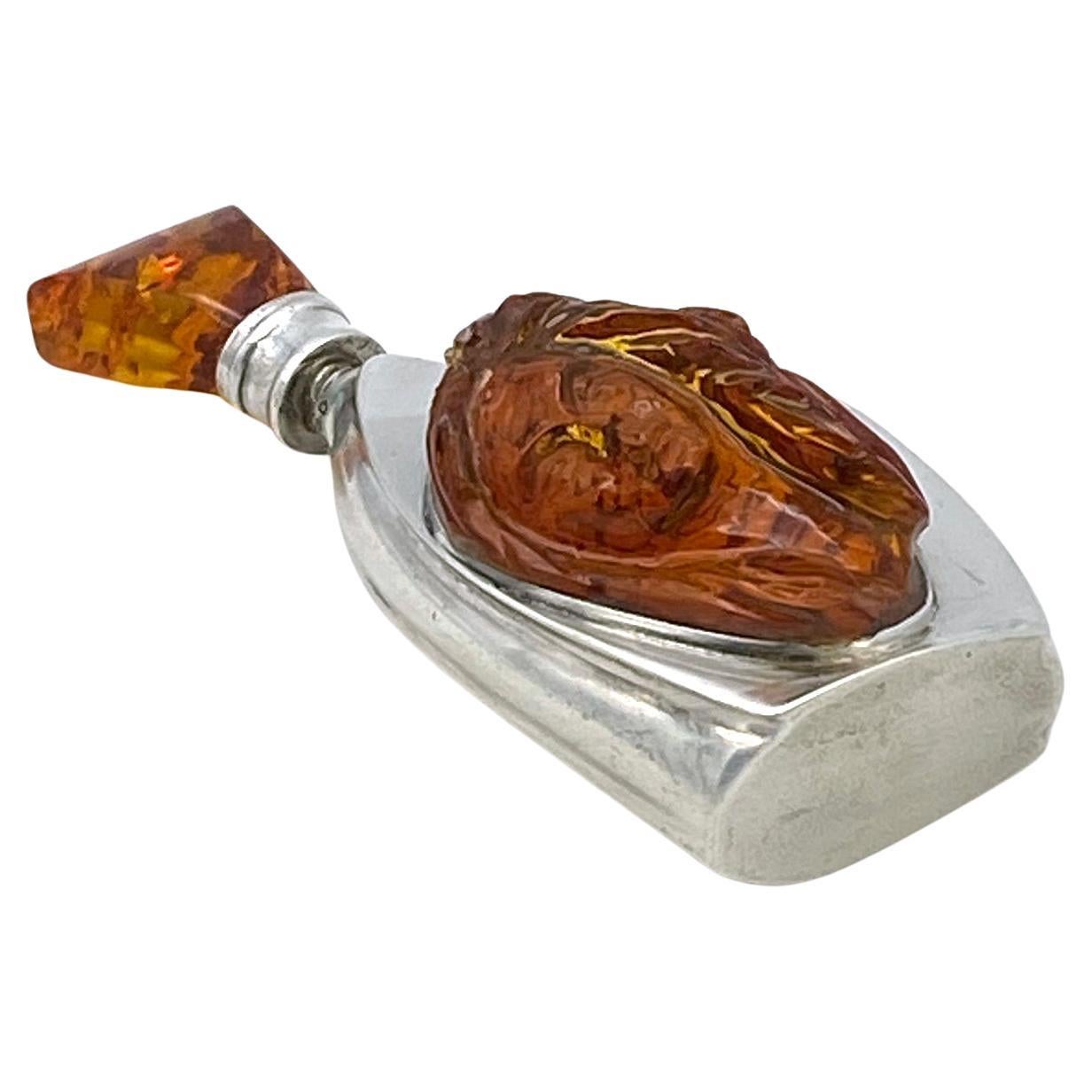 This is an Art Nouveau style sterling perfume bottle with amber. The free form sterling bottle body is mounted with a large carved long haired lady head and signed ML. The sterling stopper with dropper has a faceted amber top. This bottle is marked