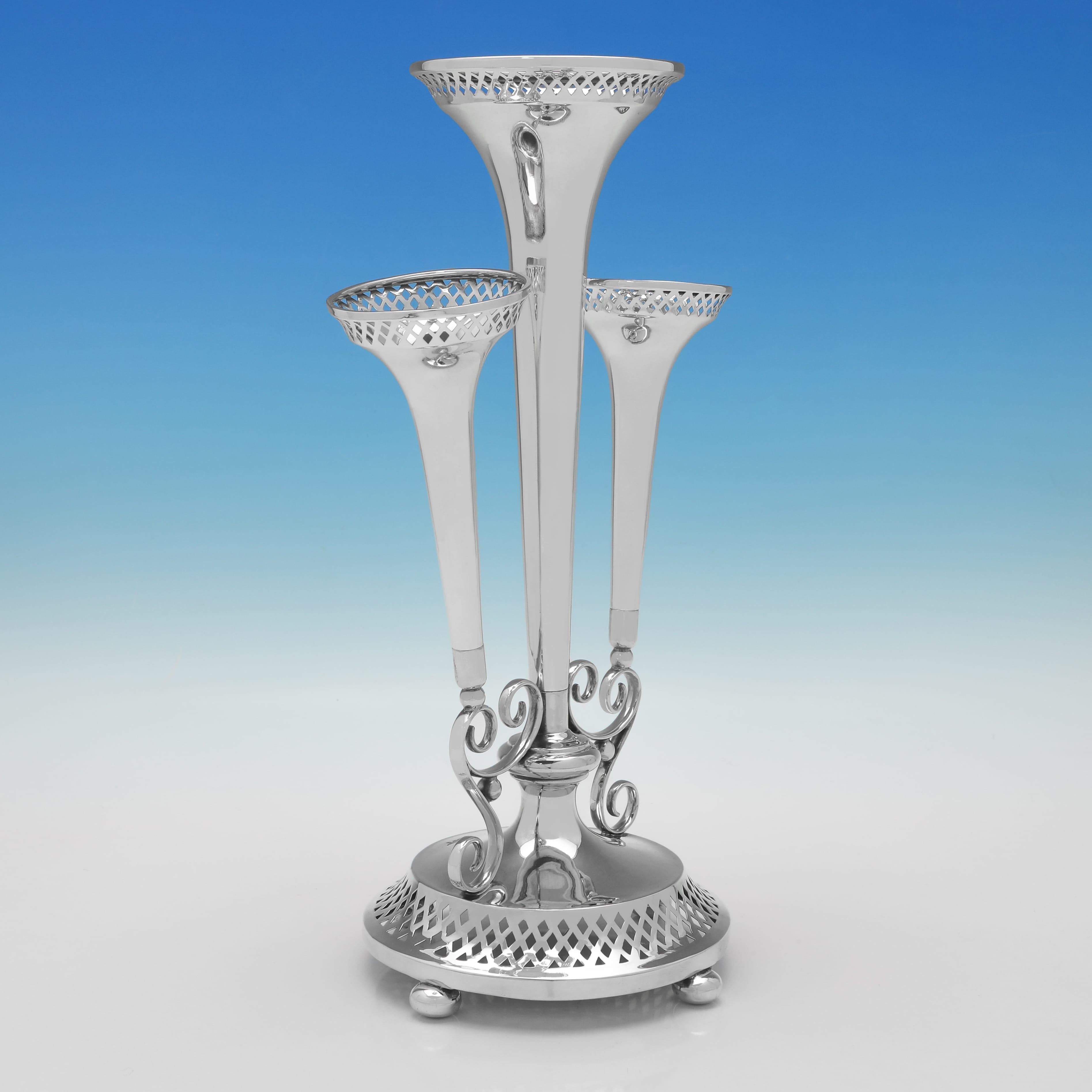 Hallmarked in Sheffield in 1911 by Walker & Hall, this Handsome, Antique Sterling Silver Epergne, features pierced decoration, four ball feet, and three trumpet vases. 

The epergne measures 13.25
