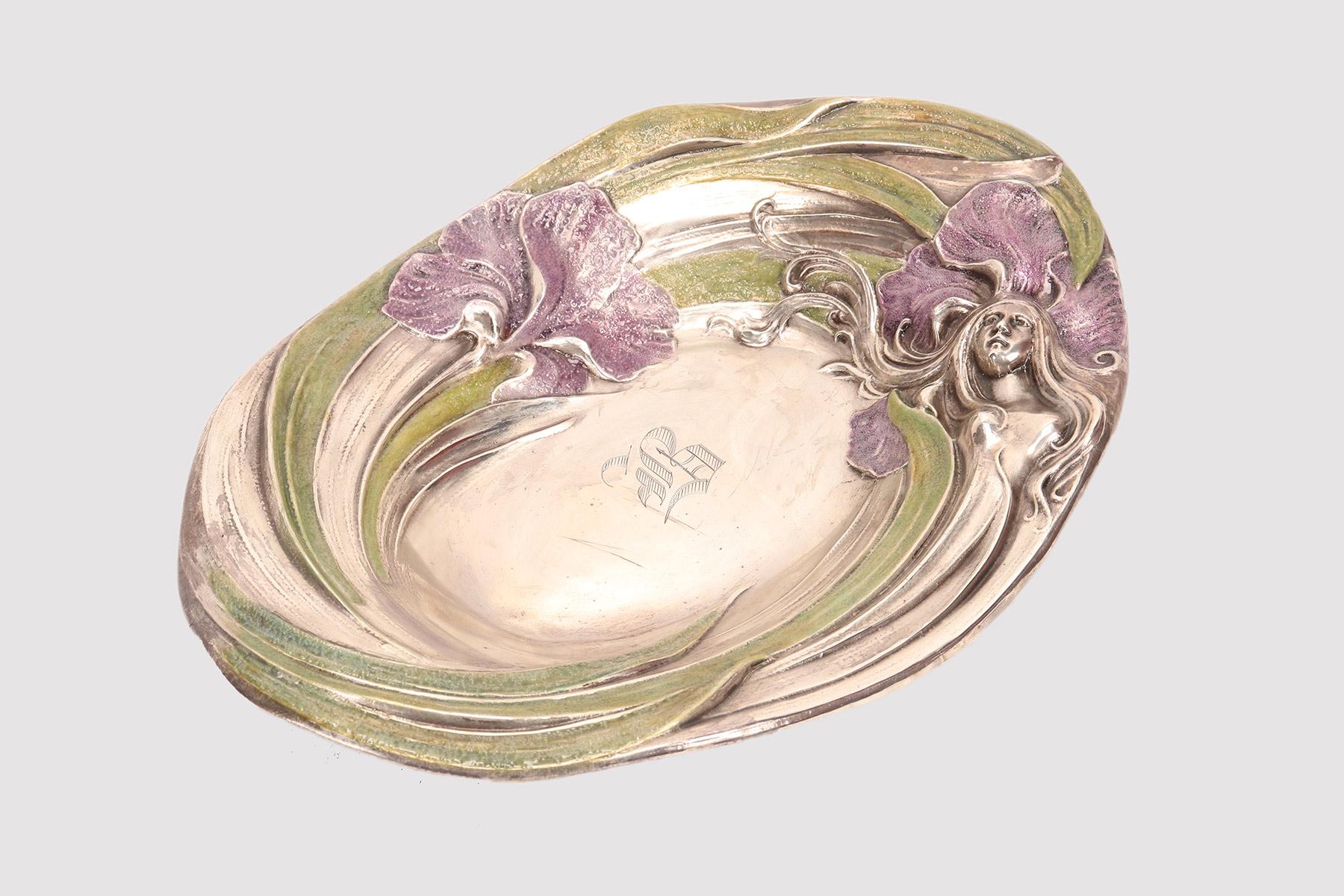 Art Nouveau oval shaped bowl in sterling silver. Embossed decoration in pure Libertry style, depicting a woman's face with long hair with enamel painted iris flowers and leaves. The Mauser Manufacturing company. Mt. Vernon, United States circa 1890.