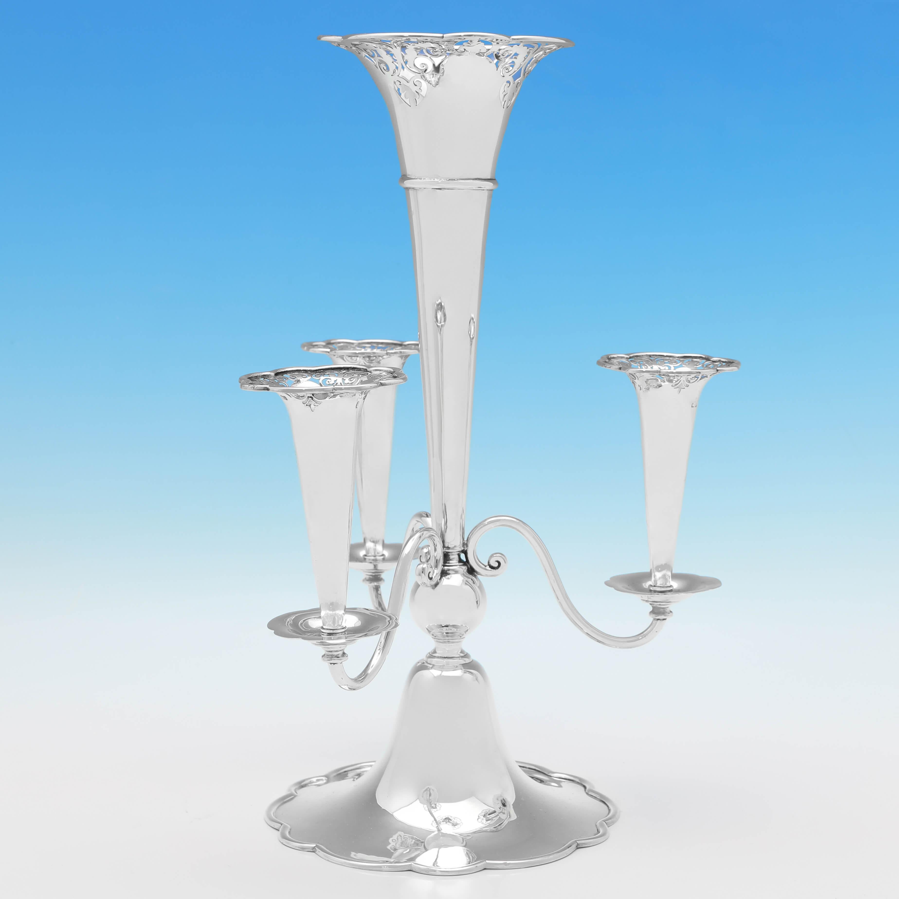 Marcada en Birmingham en 1907, esta atractiva Epergne eduardiana de plata de ley antigua es de estilo Art Nouveau, con un jarrón central más grande y 3 jarrones laterales más pequeños, todos con detalles perforados en el borde. 

La epergne mide