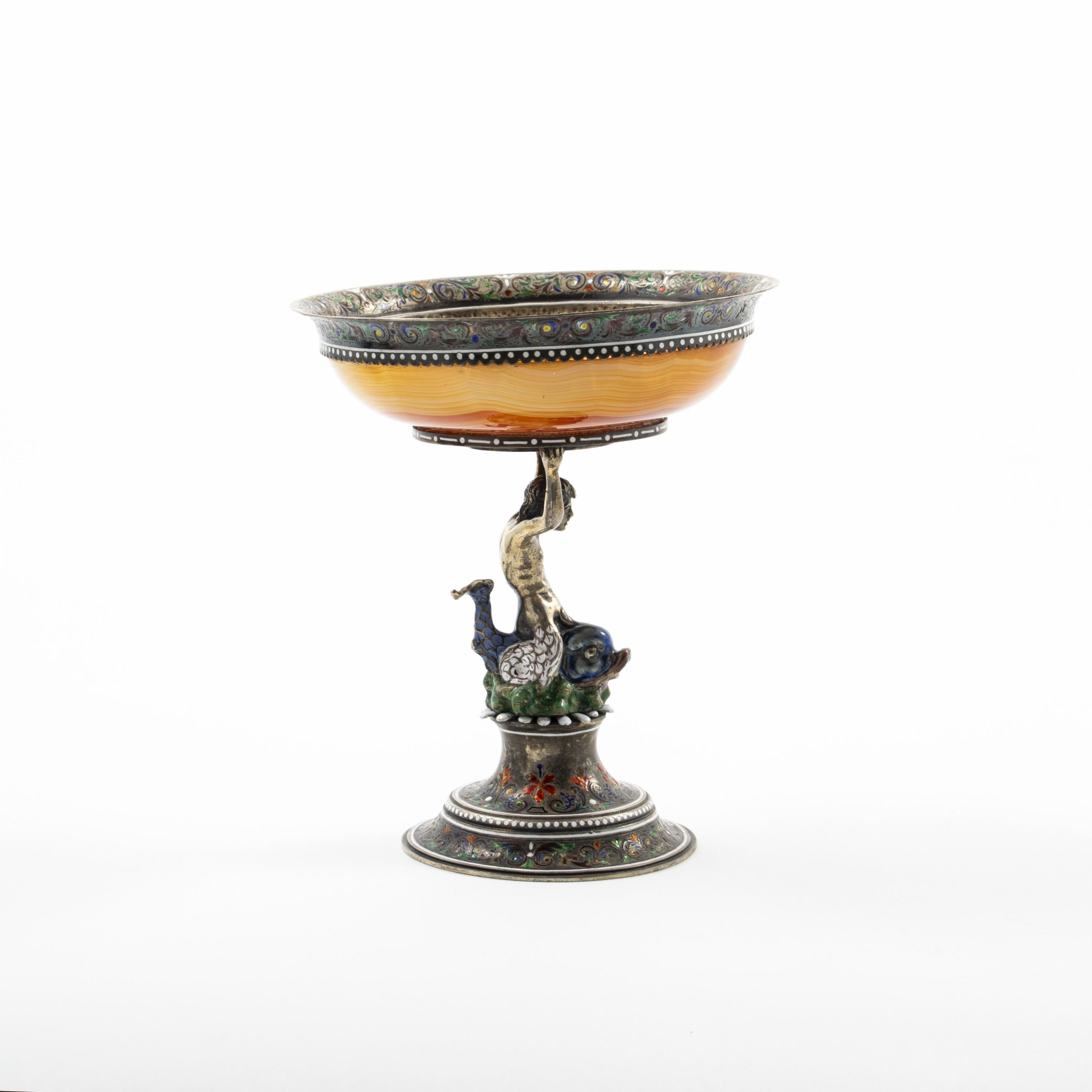 German Art Nouveau pedestal caviar server.
Agate stone bowl mounted with sterling silver adorned with enamel decorations.
Stand with figural merman sitting on top of a dolphin.
This impressive bowl was made by J.D. Schleissner and Sons of Hanau,