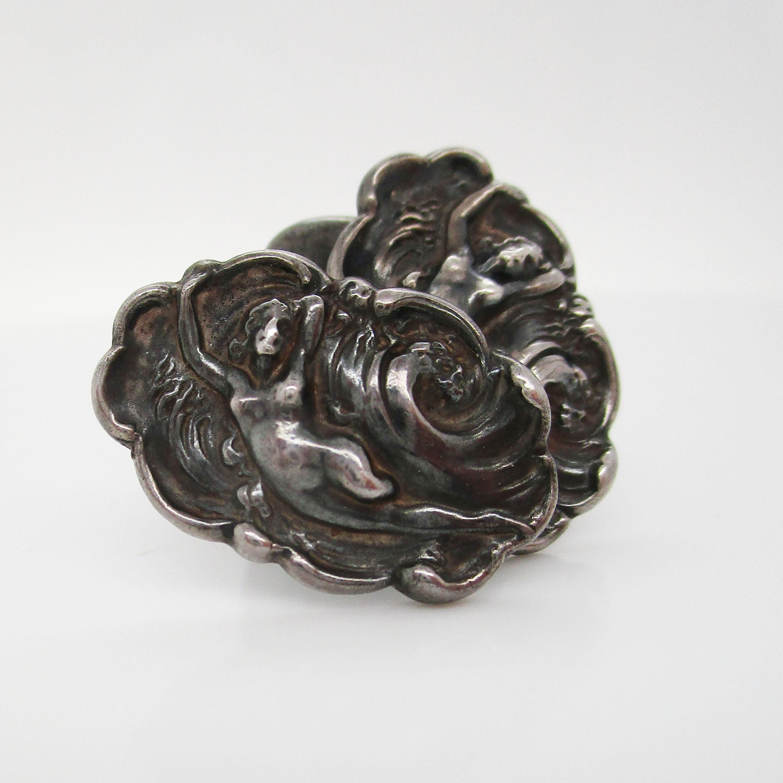 Estos preciosos gemelos son una obra de arte de principios del siglo XX. Estos eslabones de plata de ley son de los Unger Brothers y presentan una elegante representación de una mujer cabalgando sobre las olas rodeada de un borde estriado y