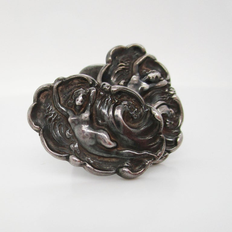 These beautiful cufflinks are a work of art from the early twentieth century. These sterling silver links are by the Unger Brothers and feature an elegant depiction of a woman riding the waves surrounded by a fluted border and delicate Art Nouveau