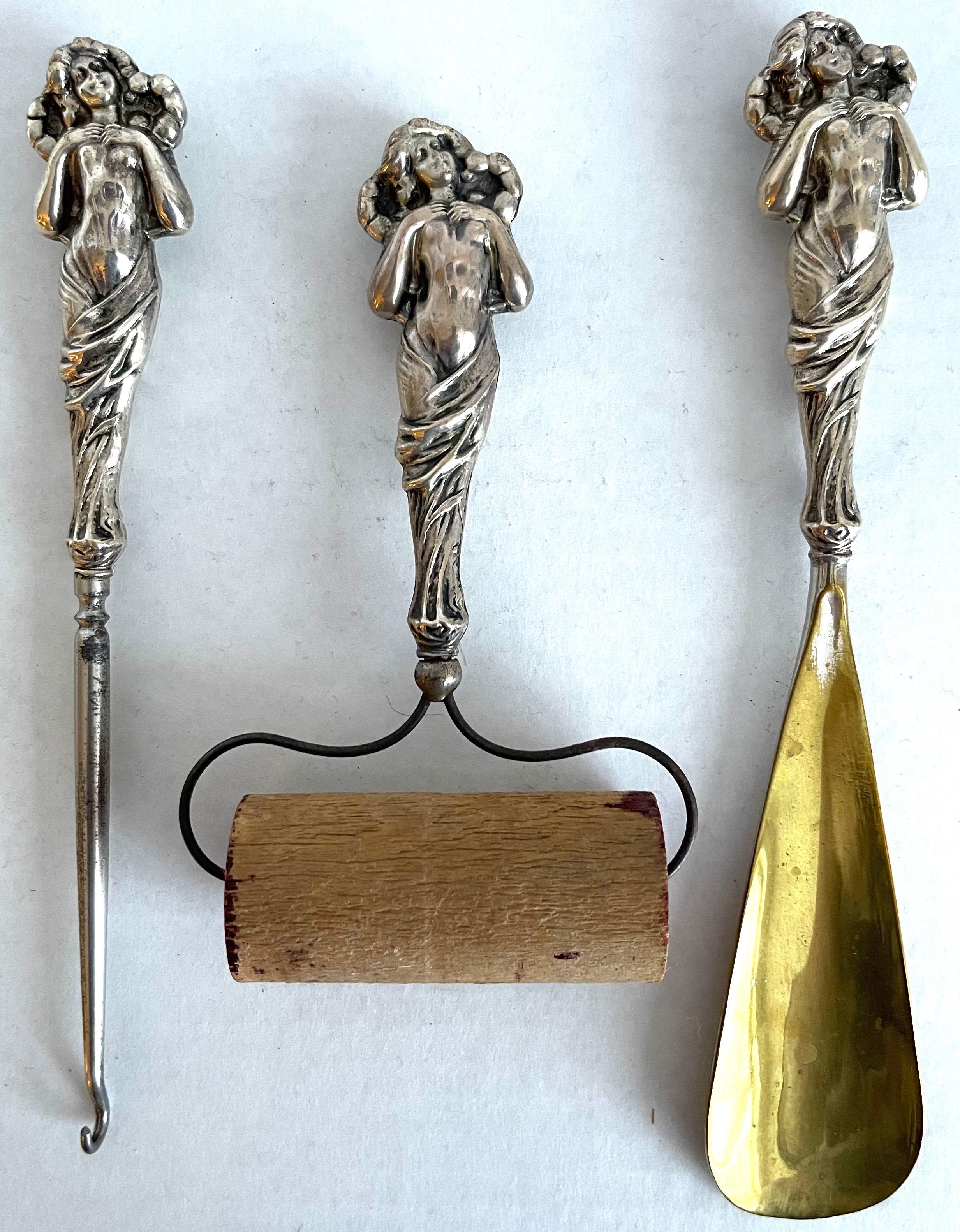 Set of 3 Art Nouveau Sterling silver vanity tools. American circa 1900. Each piece features a female figurine. Tools include, button hook, shoe horn with brass horn and roller. 
Weighted Sterling, each piece is stamped Sterling.