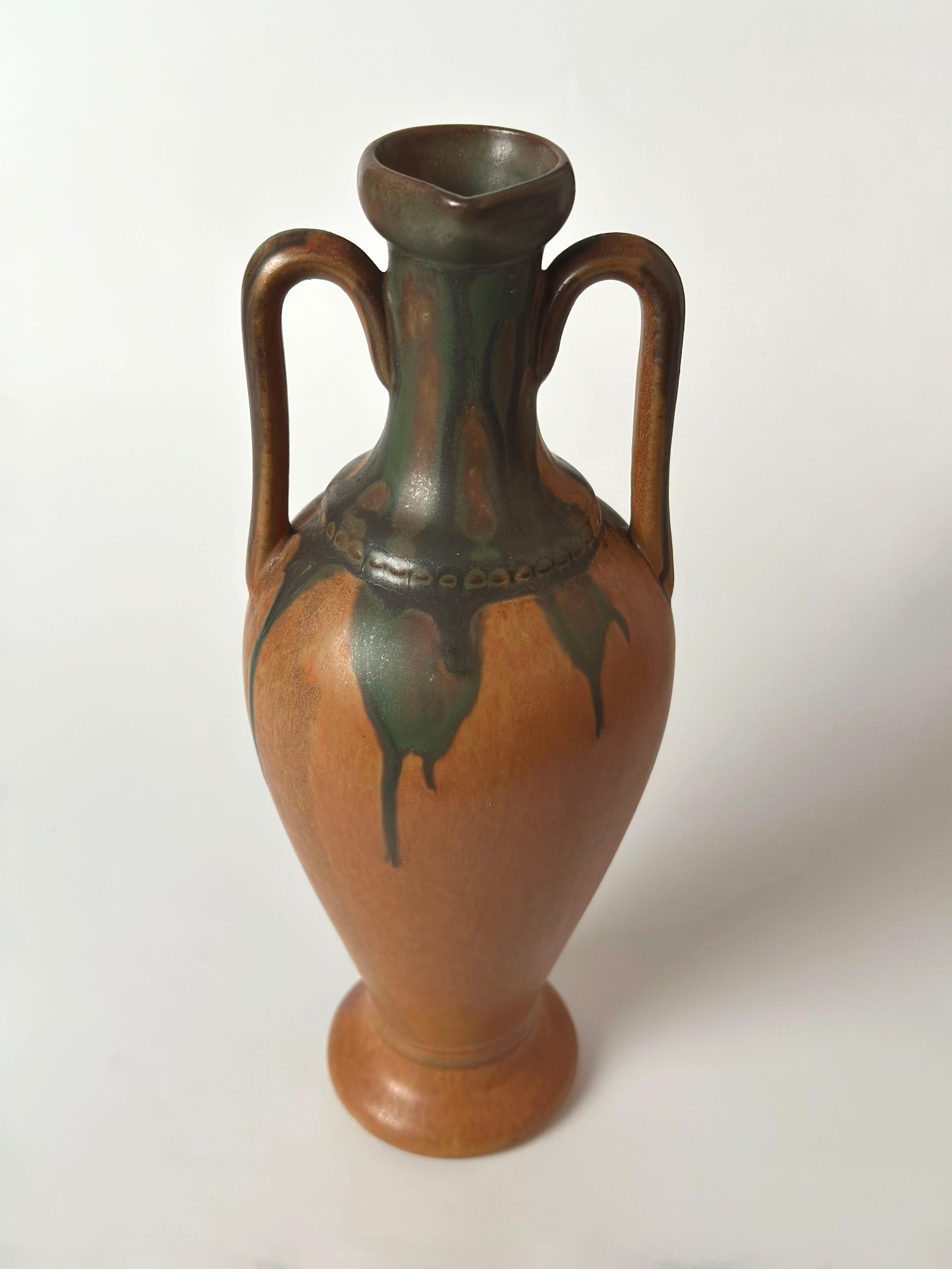 A ceramic amphora-form liqueur vessel produced by Denbac, France, in the 1950s for the iconic French spirits brand Cointreau. Commissioned as a branded serving or display piece, this tall and narrow earthenware pitcher merges commercial utility with