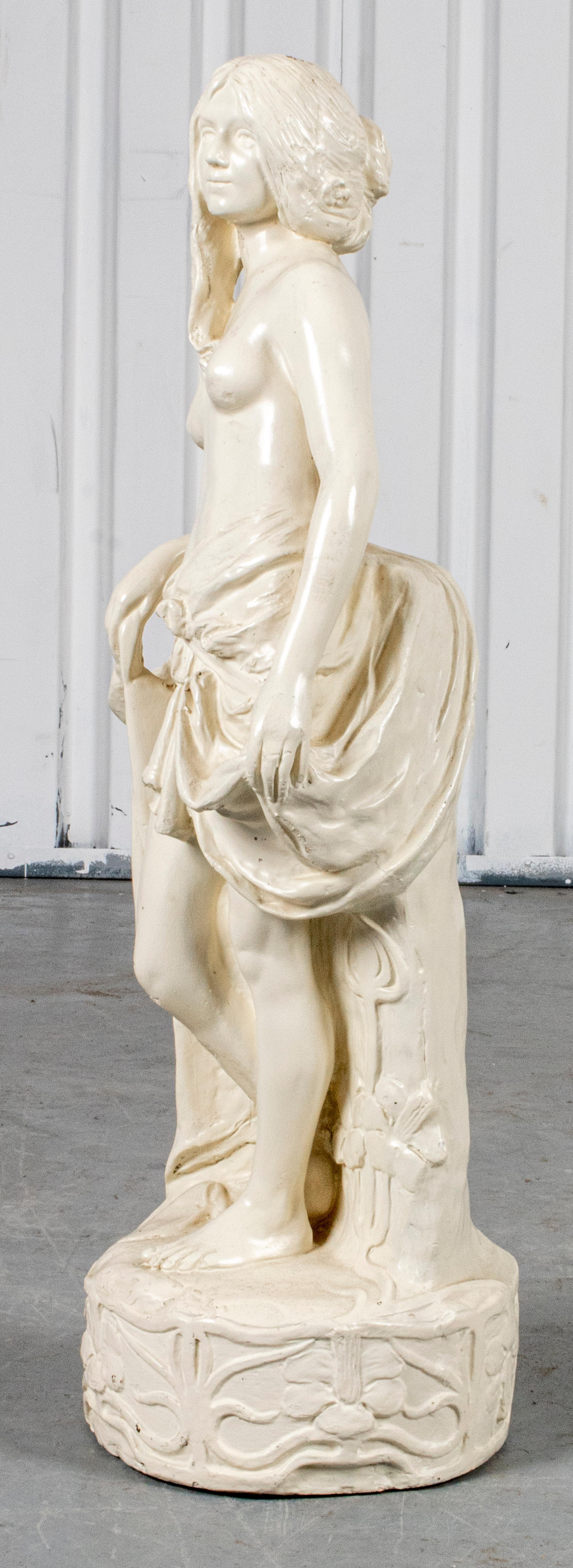 Figure de composition de style Art nouveau représentant une jeune fille, d'après l'antique, la statue étant modelée avec une robe partiellement drapée dans un paysage, signée de façon illisible à la base et avec des chiffres imprimés. 33.5
