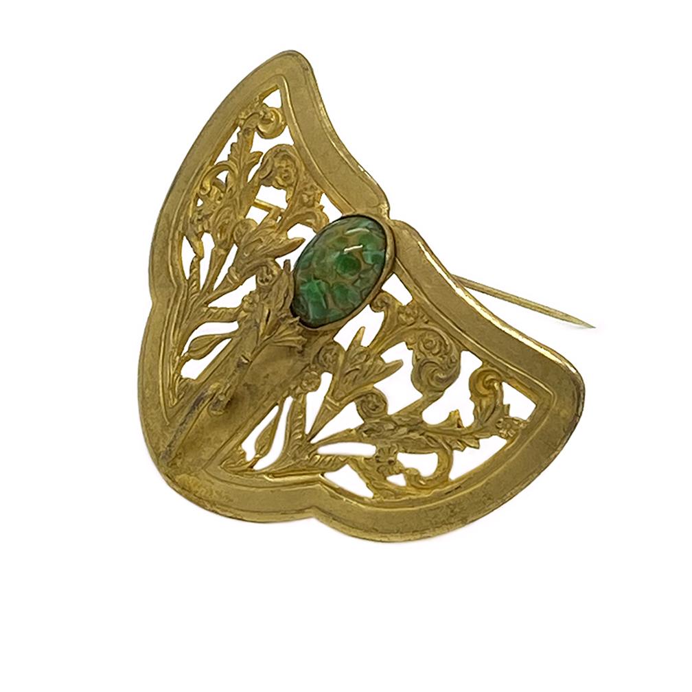 This is an Art Nouveau style gilt brooch with one piece of green art glass. The 