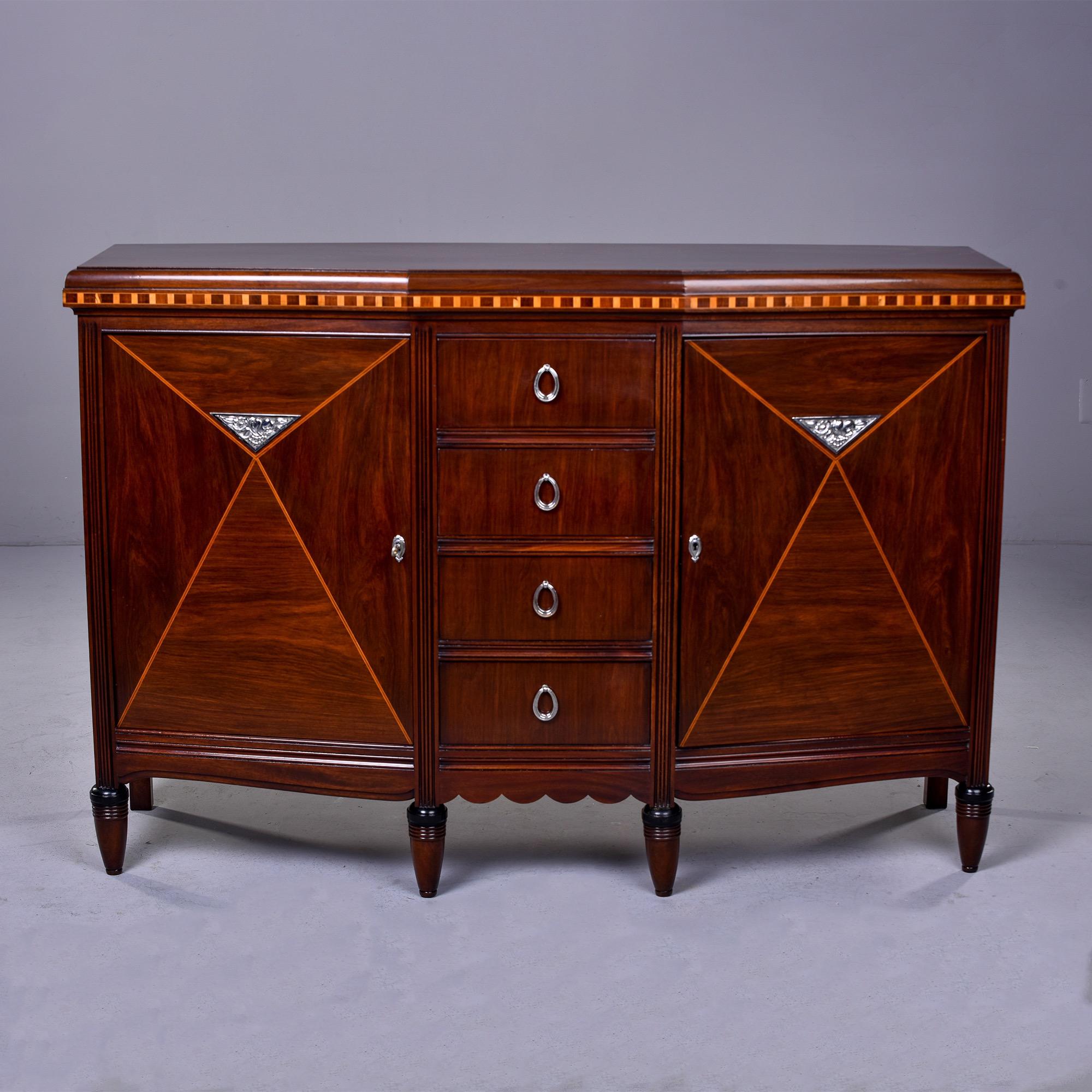 This circa 1910 Art Nouveau style mahogany side cabinet / commode was found in France. The cabinet has four front legs and two back legs. Front, top and sides have decorative inlay and parquetry work. Silver tone hardware and mounts. The center