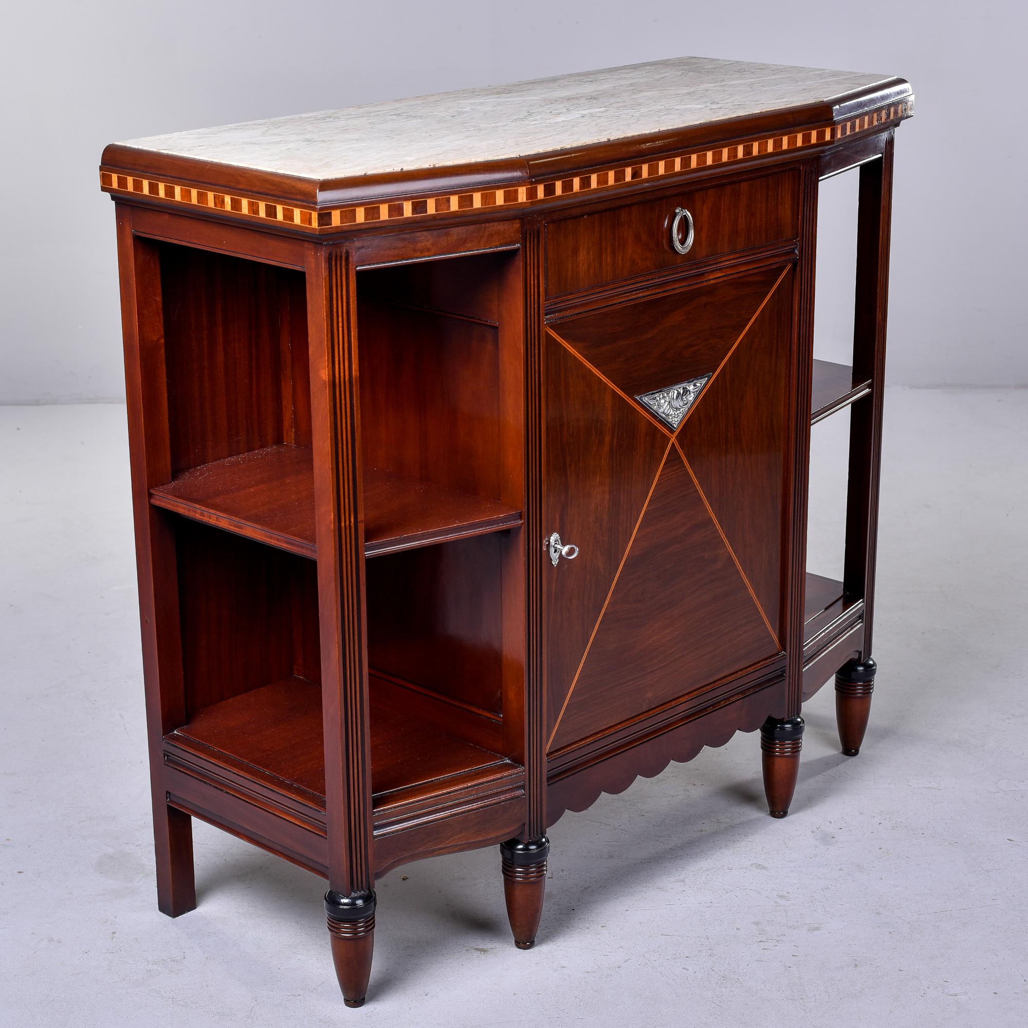 This circa 1910 Art Nouveau style marble-topped mahogany sideboard was found in France. The cabinet has four front legs and two back legs. Sideboard is topped with a pale beige marble and the front edge and cabinet door feature decorative inlay and