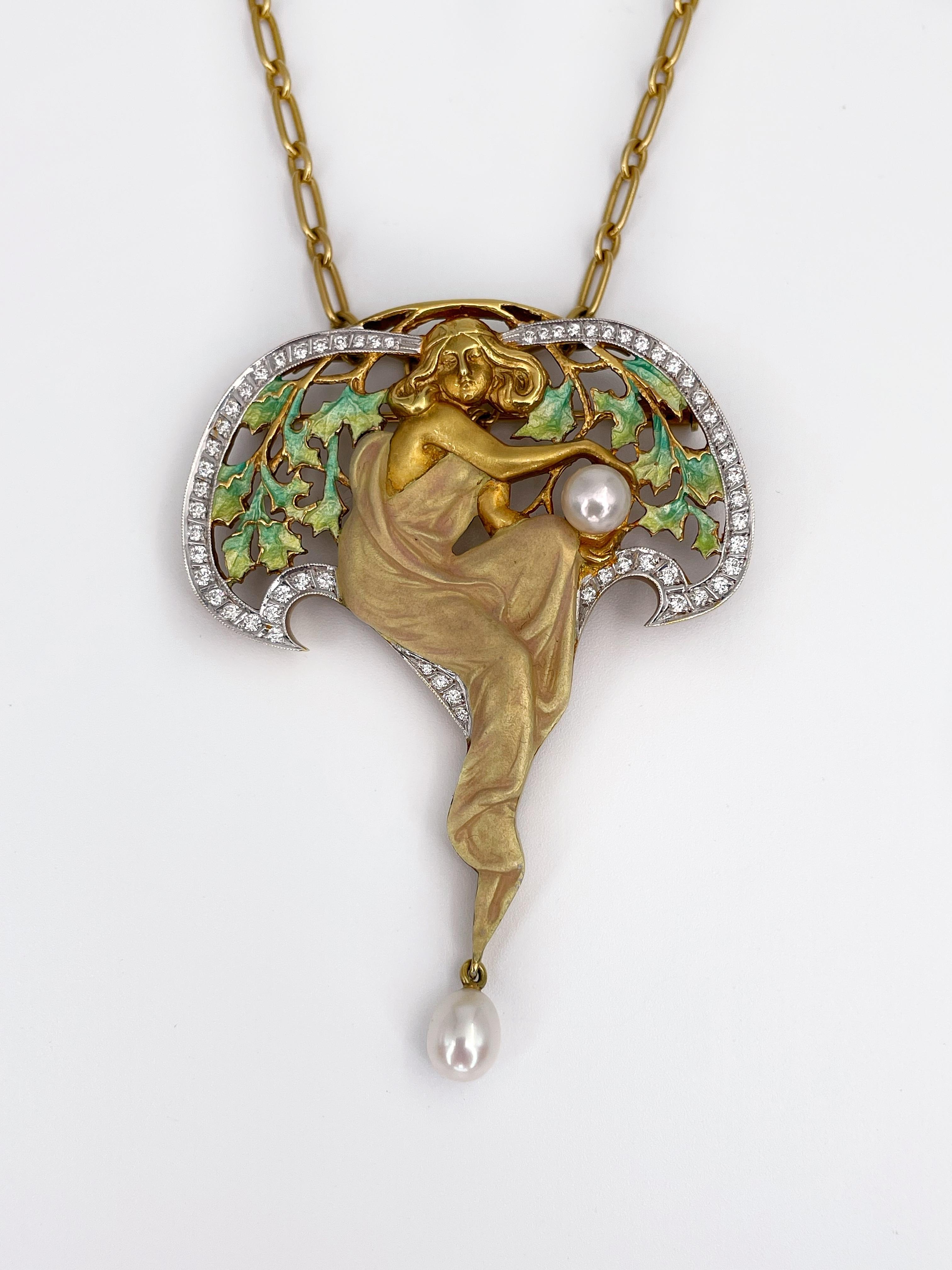 This is a breathtaking Art Nouveau style lavalier pendant-brooch designed by Masriera. It depicts a nymph framed by floral motifs. 

The piece is crafted in 18K yellow gold. It features 58 round brilliant cut diamonds and 2 cultured pearls. Pendant