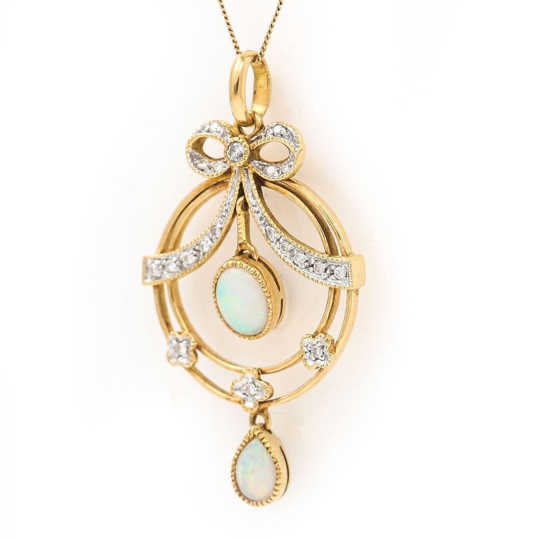 A very pretty Art Nouveau style drop pendant set in 9ct yellow and white gold with precious opal and diamond. Taking inspiration from the typical motifs seen at the beginning of the 20th century, the pendant has a diamond set bow and ribbon detail