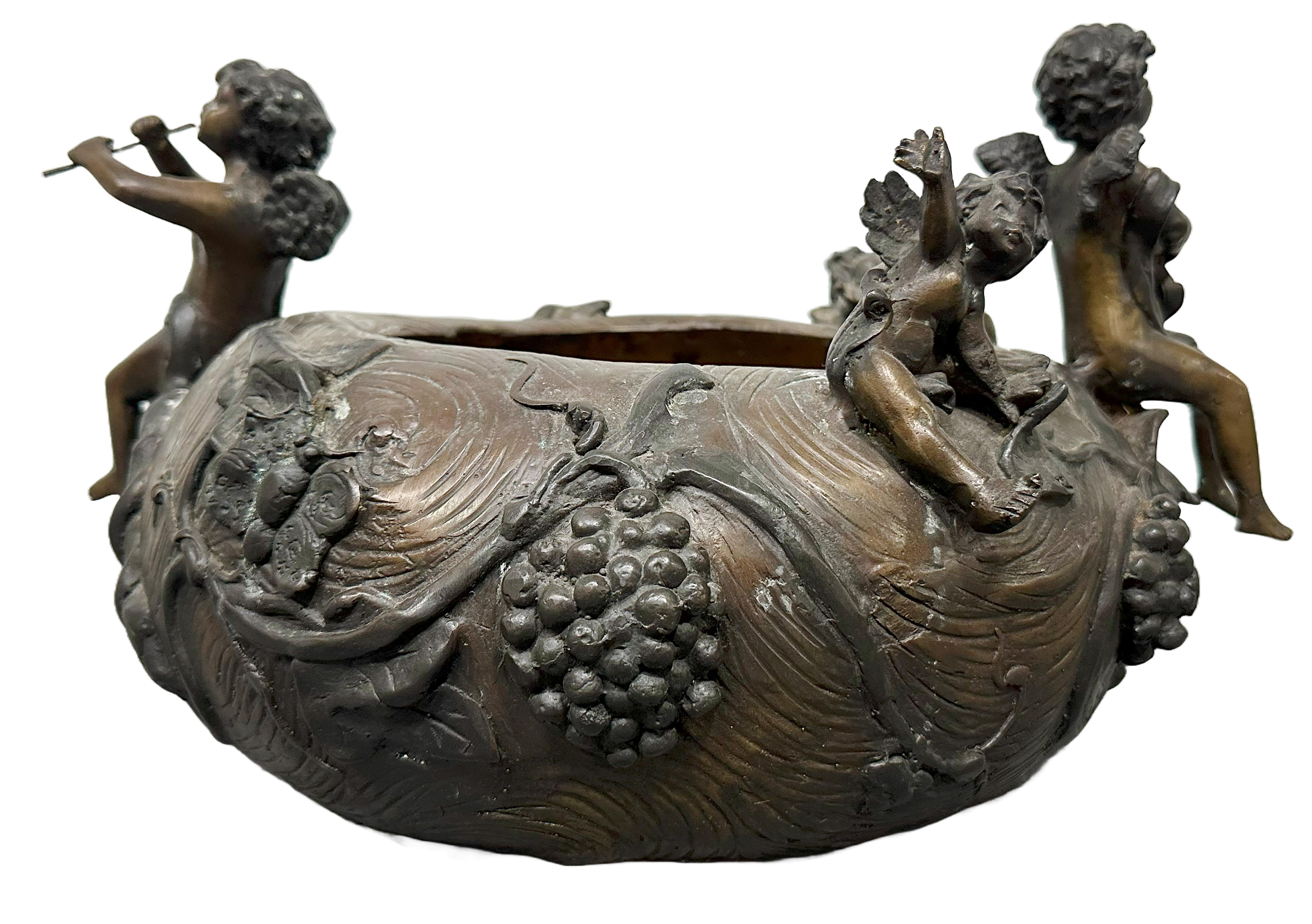 Une charmante pièce d'époque de style art nouveau  Pot de jardinage avec des chérubins jouant de la flûte. Sculptures texturées représentant des vents, des vignes et d'autres instruments. Fabriqué au 20e siècle. 

Aucune marque évidente sur la