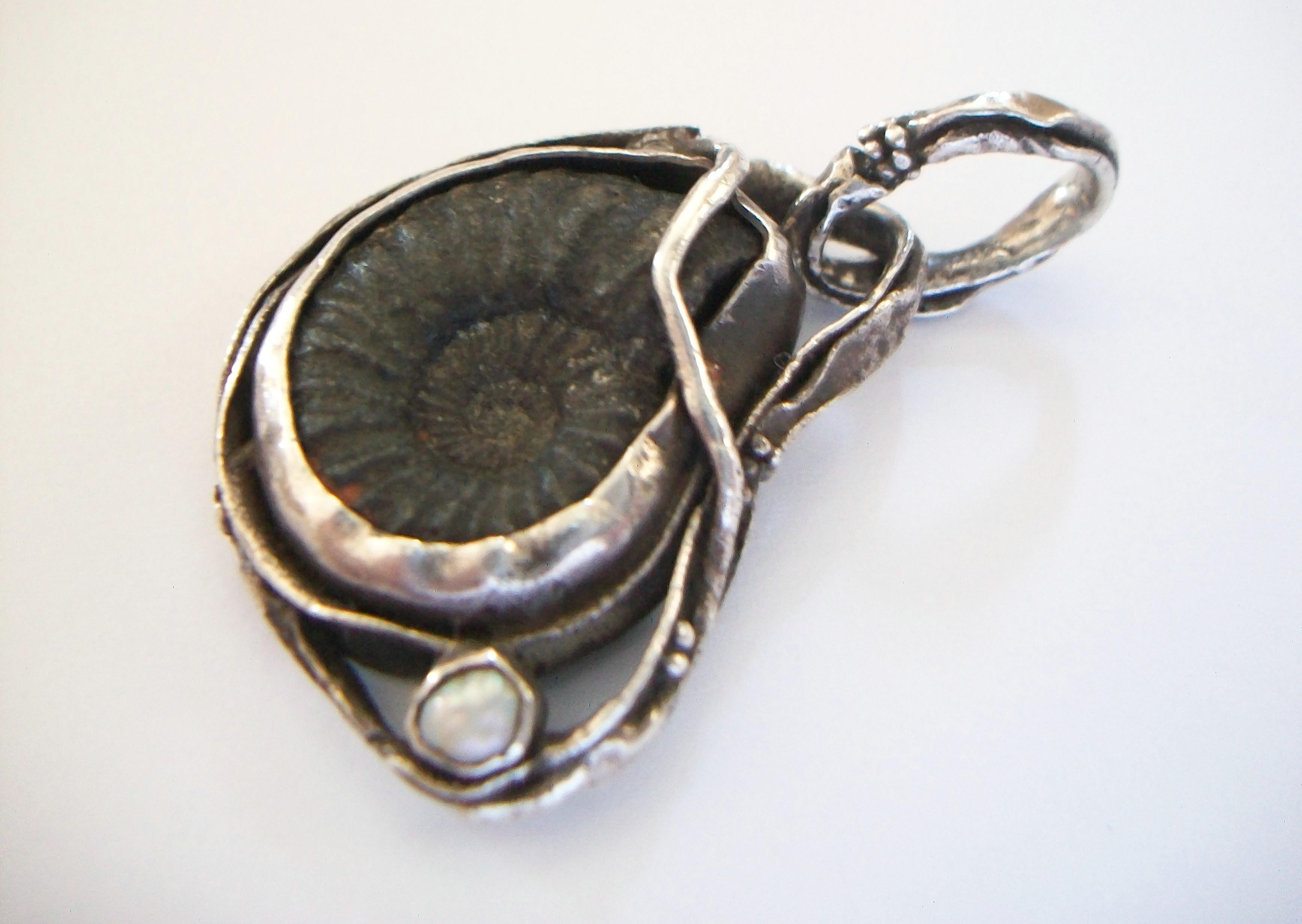 Art Nouveau style Pyritized Ammonite Fossil & Cultured Baroque Pearl pendant - organically set in white metal (unknown content) - hand made - large bale - warm aged patina - unsigned - 20th century.

Excellent vintage condition - all original -