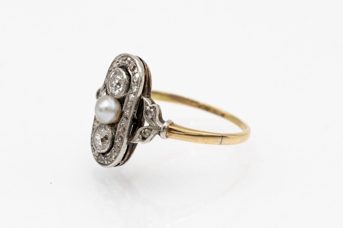 Anello antico in oro 14 carati e platino in stile Art Deco. L'anello è decorato con due diamanti taglio vecchio, del peso di circa 0,30 ct. Colore: F-G e purezza: SI. Ai lati, 28 diamanti antichi taglio rosa e una perla d'acqua salata coltivata al