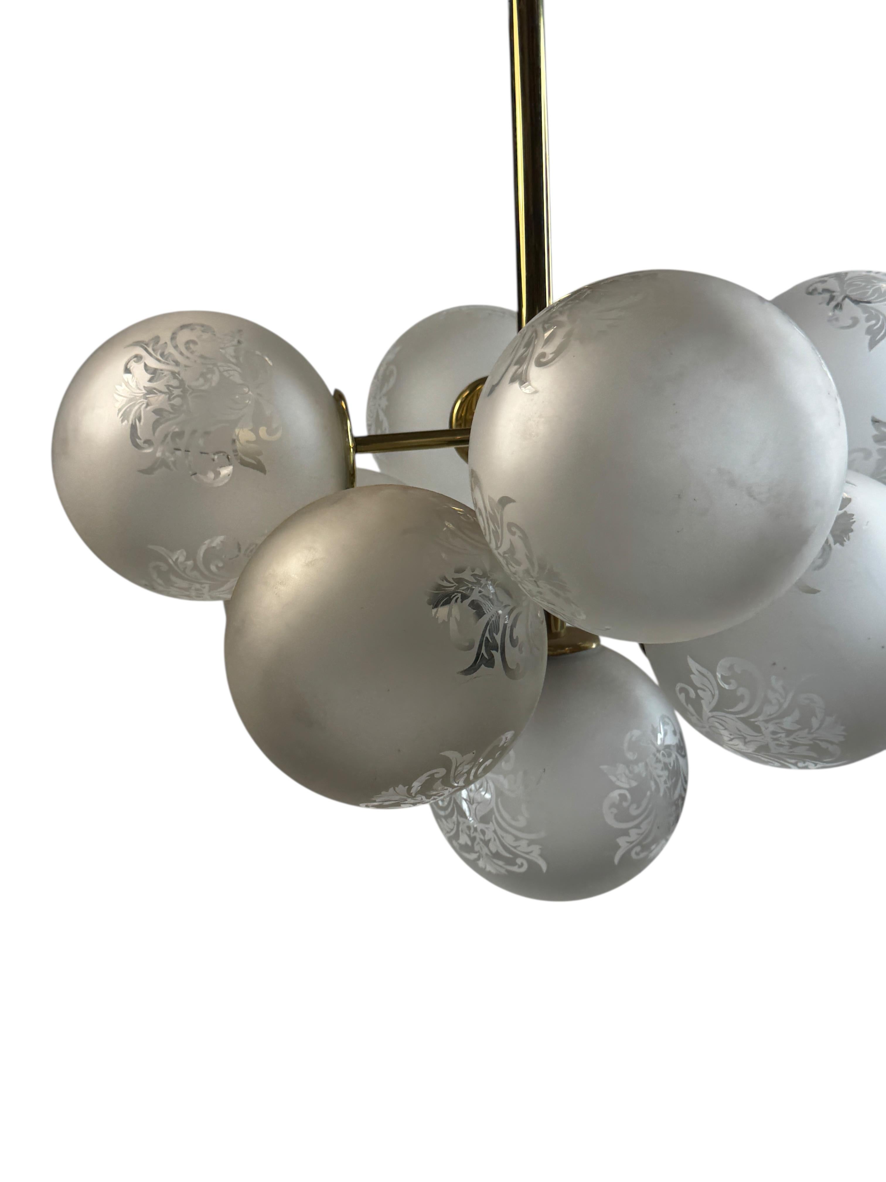 Muy decorativa y bella lámpara de araña de latón, provista de nueve enchufes E14 con superficie satinada y adornos florales en tulipas de bolas de cristal de diseño Art Nouveau. La araña vintage de latón dorado y cristal de superficie satinada de