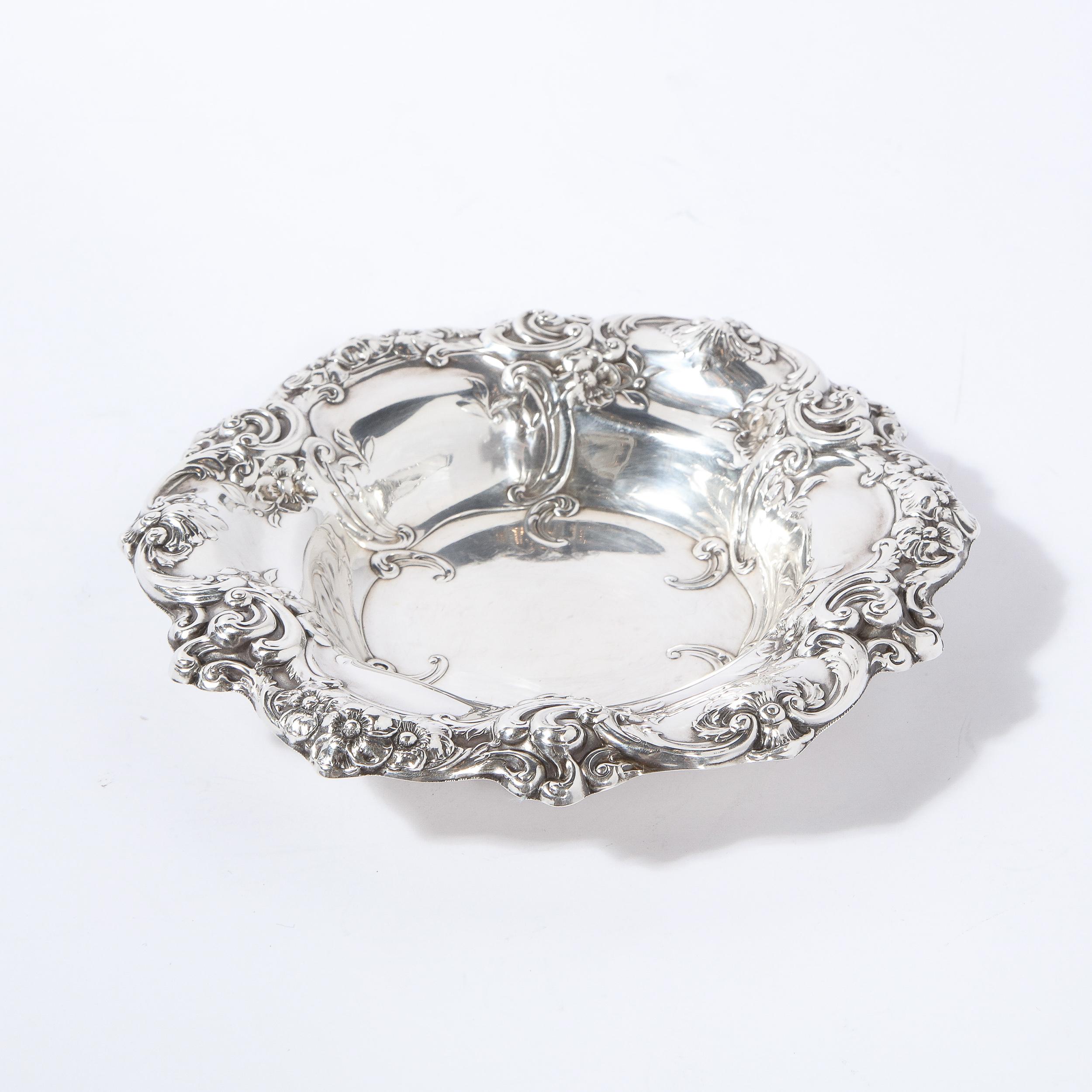 This stunning Art Nouveau/ Neoclassical style sterling silver decorative dish was realized by Gorham Silversmiths. It features a circular base and a raised scalloped border with a wealth of curvilinear and abstracted stylized foliate and floral
