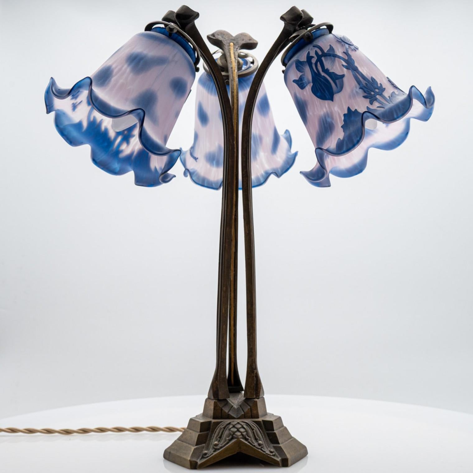 
This is a Vianne table lamp, made around the 1970s in France.

The lamp features a brass base and 3 arms with blue and clear glass shades with a floral pattern on it. Illuminates beautifully.

 ;


