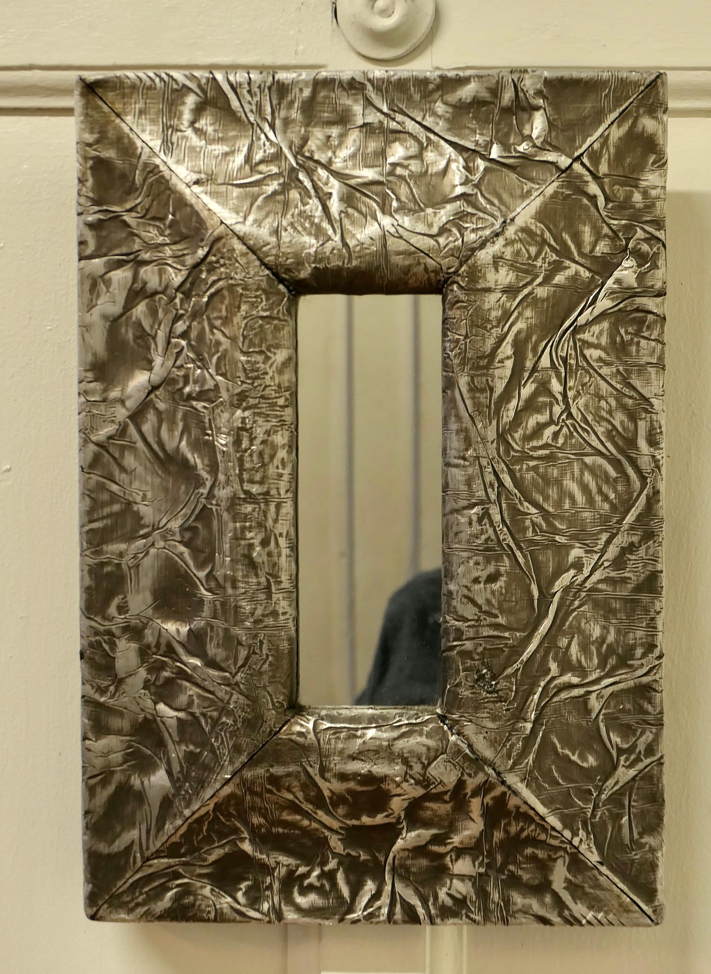 Art Nouveau style wall mirror, made in Hand Beaten Metal.

This is an unusual piece, it has a 4” wide hammered metal frame, this has pewter patination. 
The Mirror frame has a very naturalistic abstract look, and in the centre a small rectangular