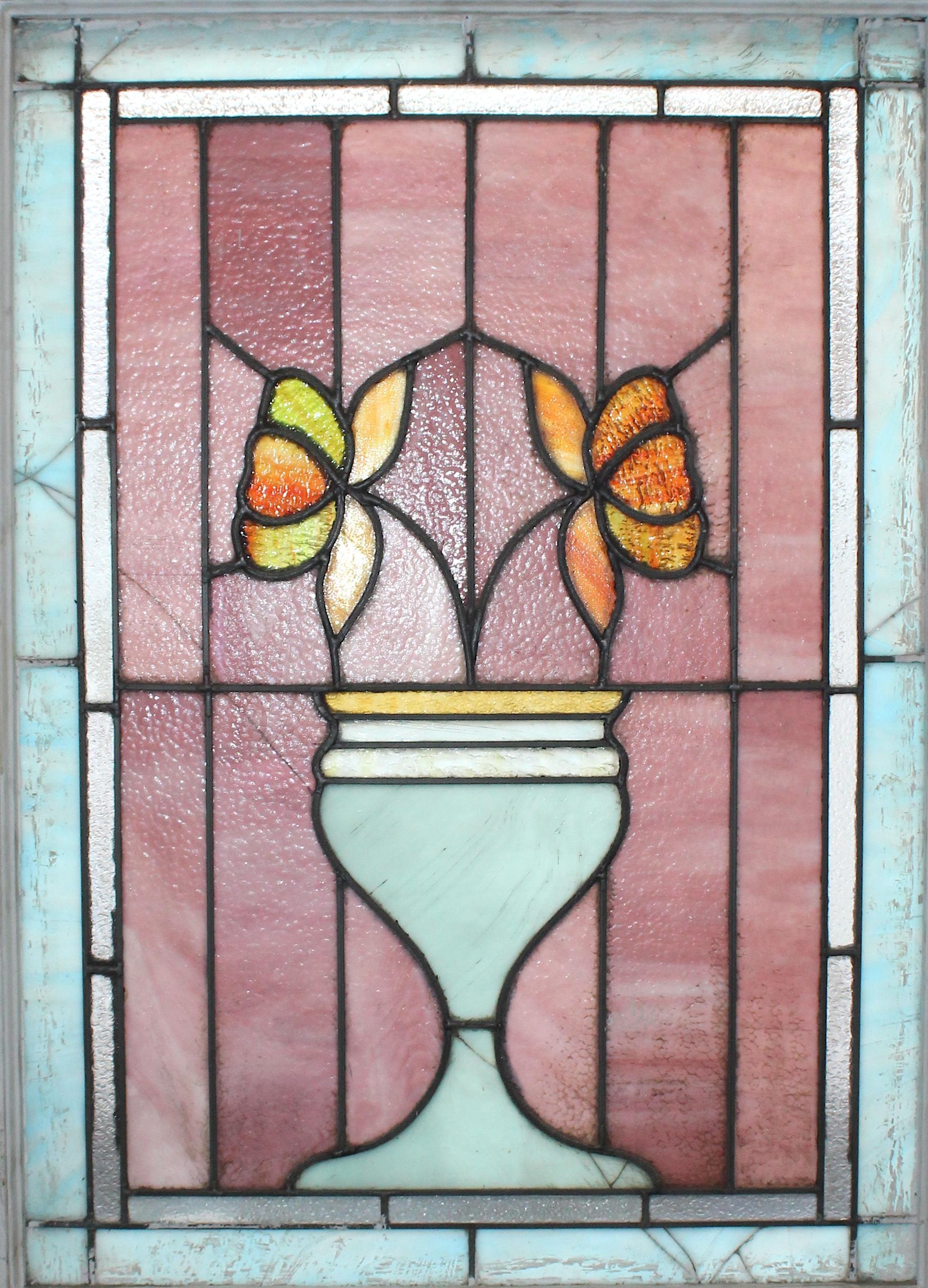 This antique window comes from the parlor of a brownstone in Brooklyn NY. A beautiful play of baby blue and rich pink glass are accentuated by the golden pedals of the two flowers emerging out of the vase.
Currently housed in a wooden frame - the