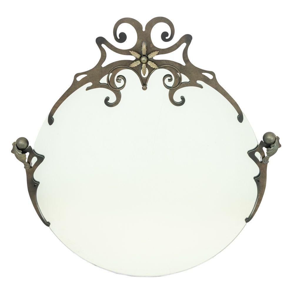 Espejo circular de hierro forjado de estilo Art Nouveau, la cresta en forma de voluta perforada con forma de bola y apliques florales. Alto 42
