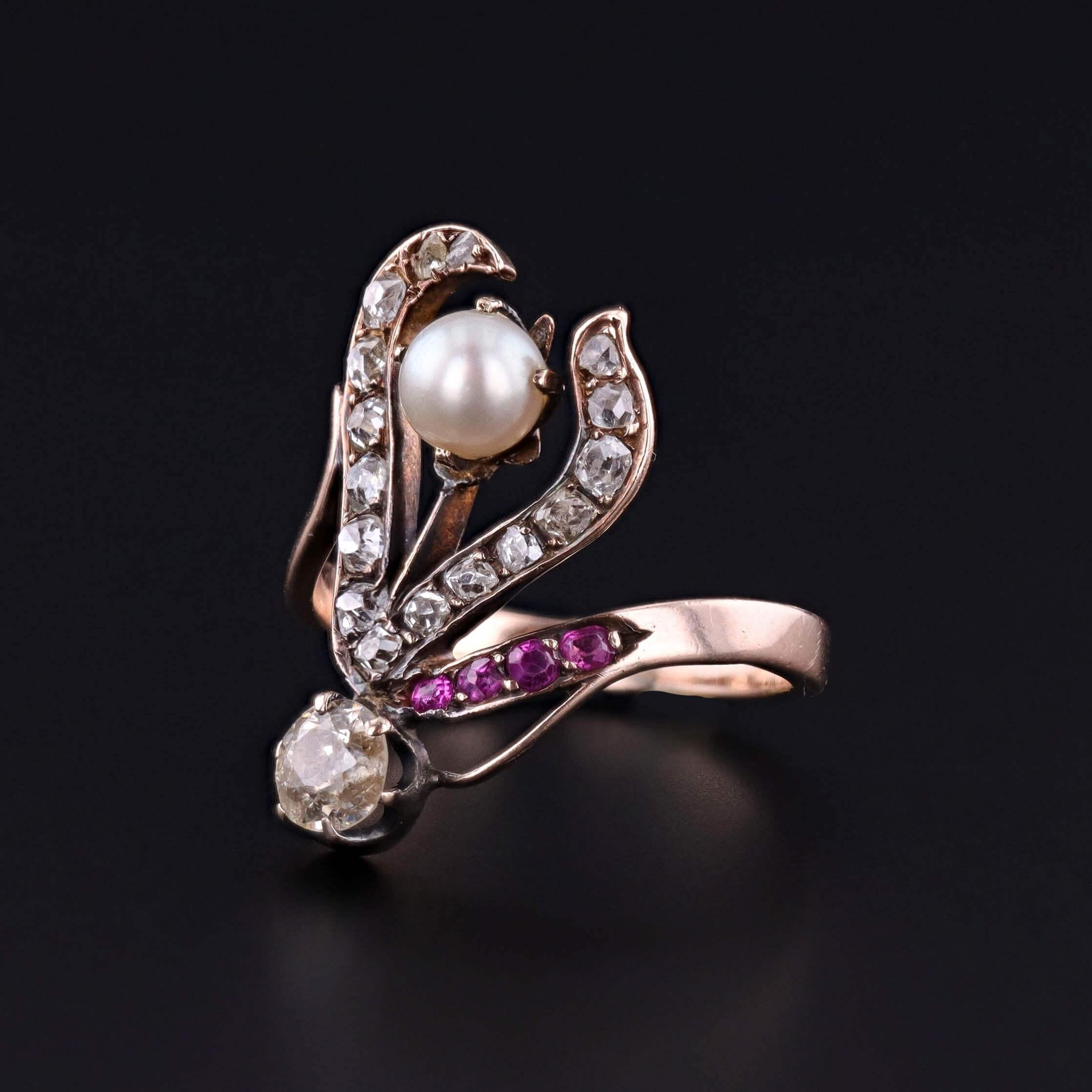 Gracieuse bague Art Nouveau (vers 1890-1900), présentant une fleur stylisée et fluide sertie de diamants étincelants, de rubis éclatants et d'une perle unique lustrée, le tout réalisé en or rose 10k. Les courbes organiques et l'asymétrie romantique