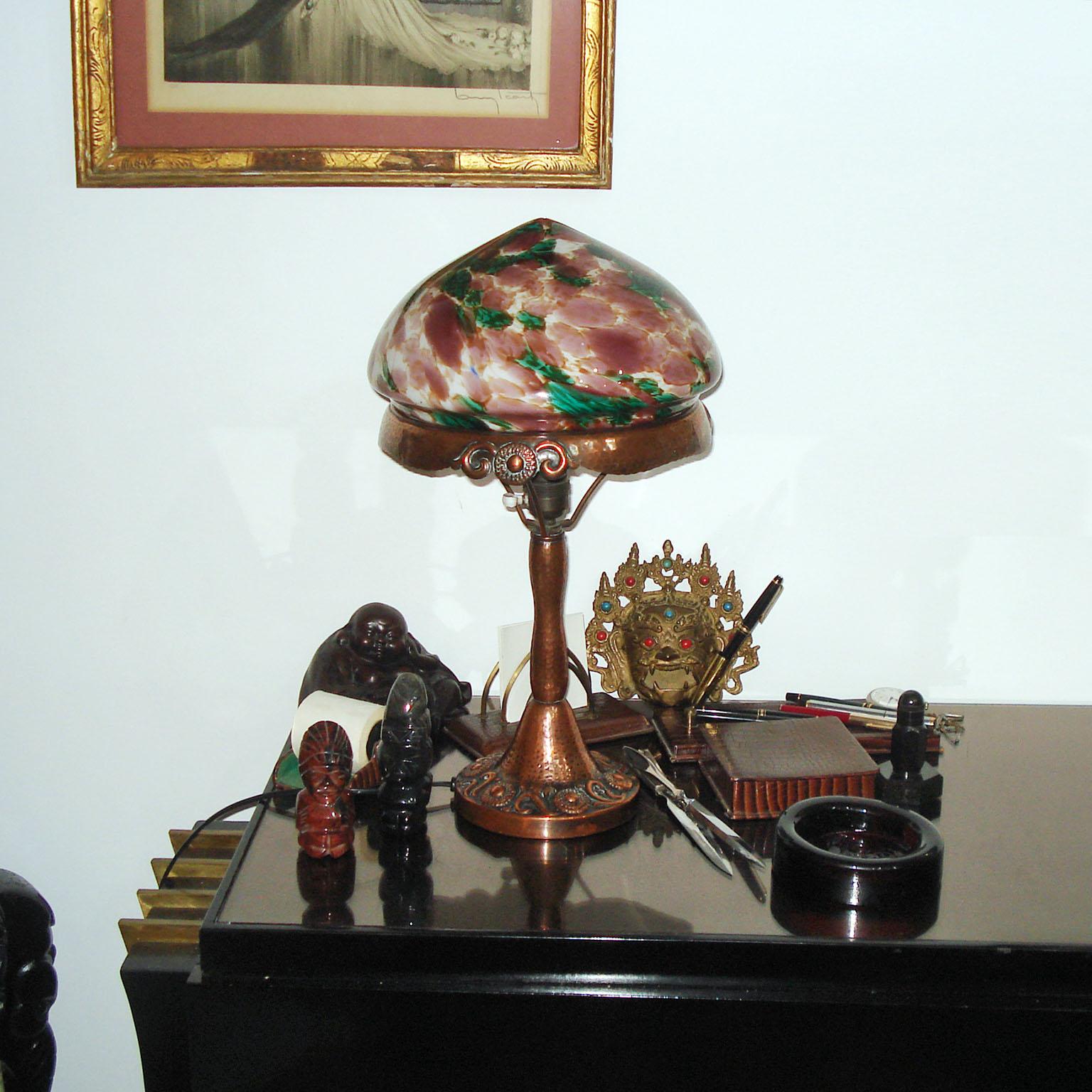 A beautiful representative Jugendstil / Art Nouveau table lamp, made of hammered copper with a glass dome, made of an under layer of opaline glass cover by a colored layer of marbleized glass in shades of purple, green, white, making a very cozy