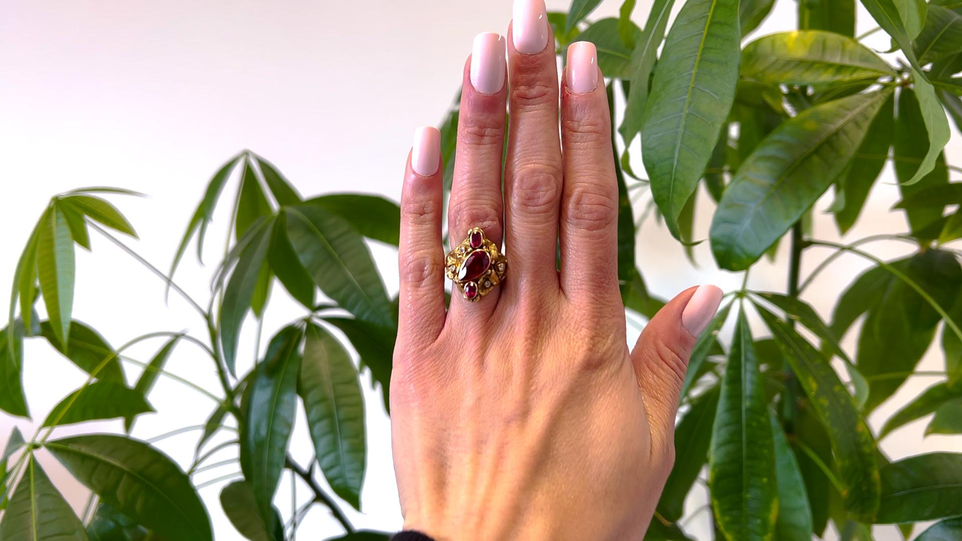 One Art Nouveau Synthetic Ruby and Diamond 14k Yellow Gold Ring. Featuring one pear cut and two oval mixed cut synthetic rubies. Accented by four single cut diamonds with a total weight of approximately 0.10 carat, graded I color, I1 clarity.