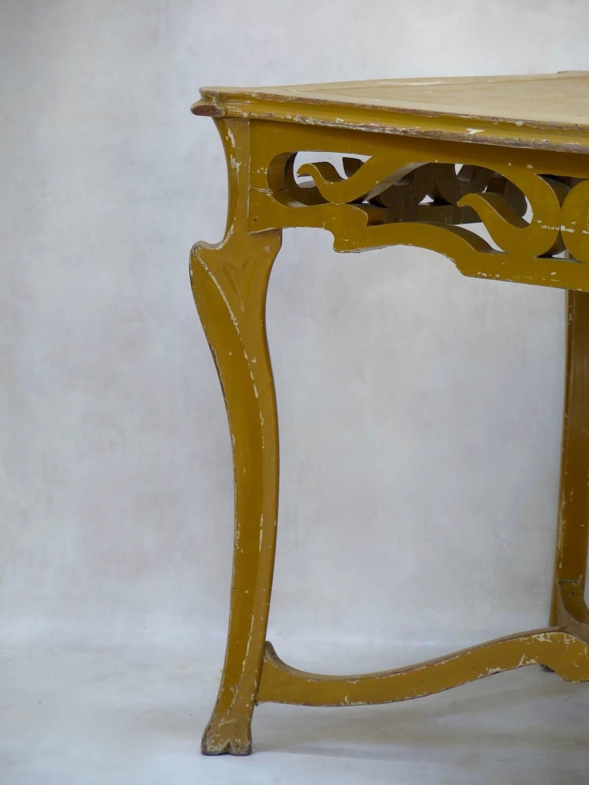 Französischer Jugendstiltisch aus geschnitztem Holz mit einer harzartigen Platte. Original senfgelbe Farbe. Der Tisch hat die angenehmen, fließenden Linien, die für diesen Stil charakteristisch sind, aber auch eine schöne Stämmigkeit, die ihn so