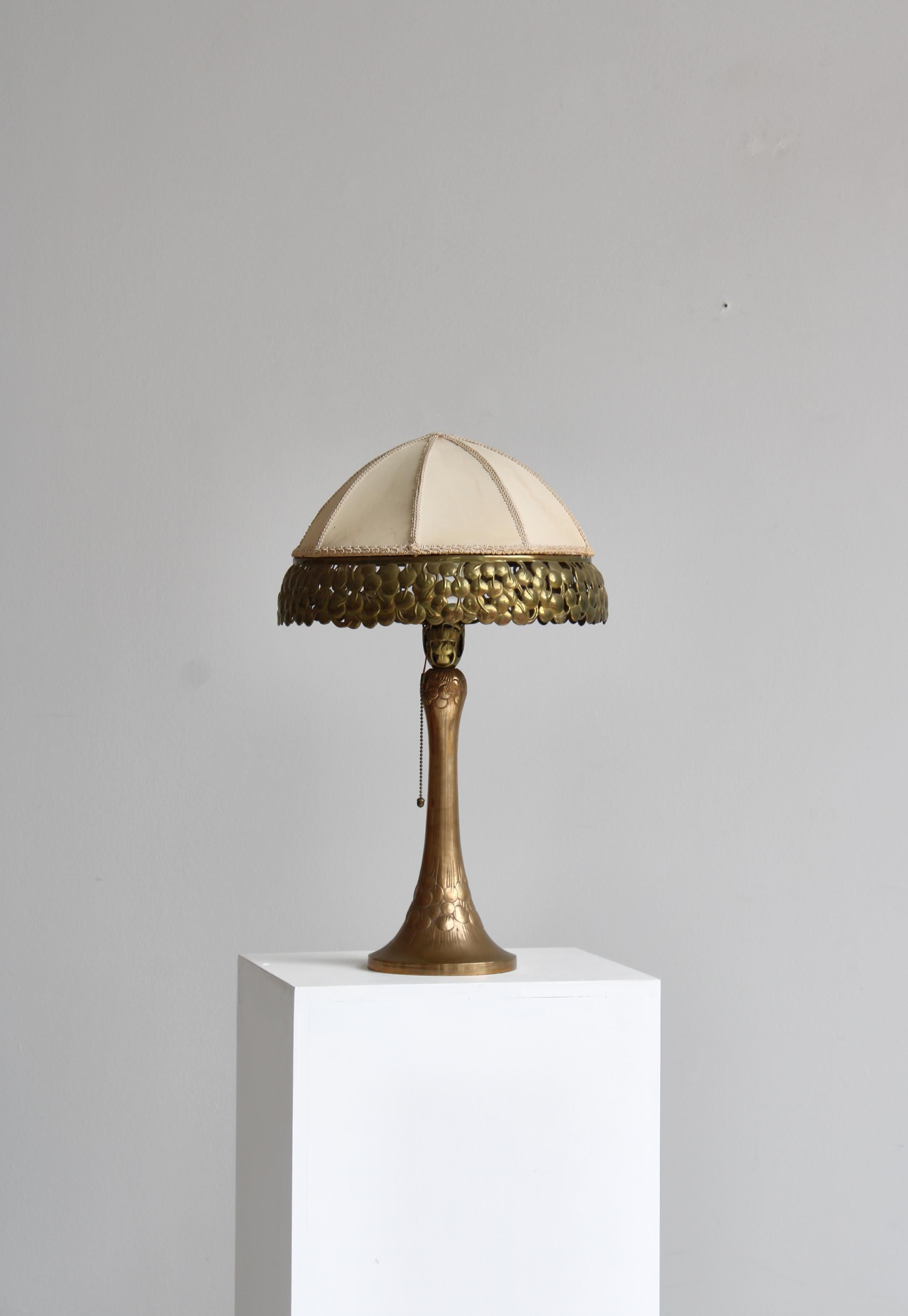Handmade art nouveau brass table lamp by Mogens Ballin enchased with organic relief decor. Lamp shade covered with light fabric and mounted with openwork brass rim. Stamped monogram 