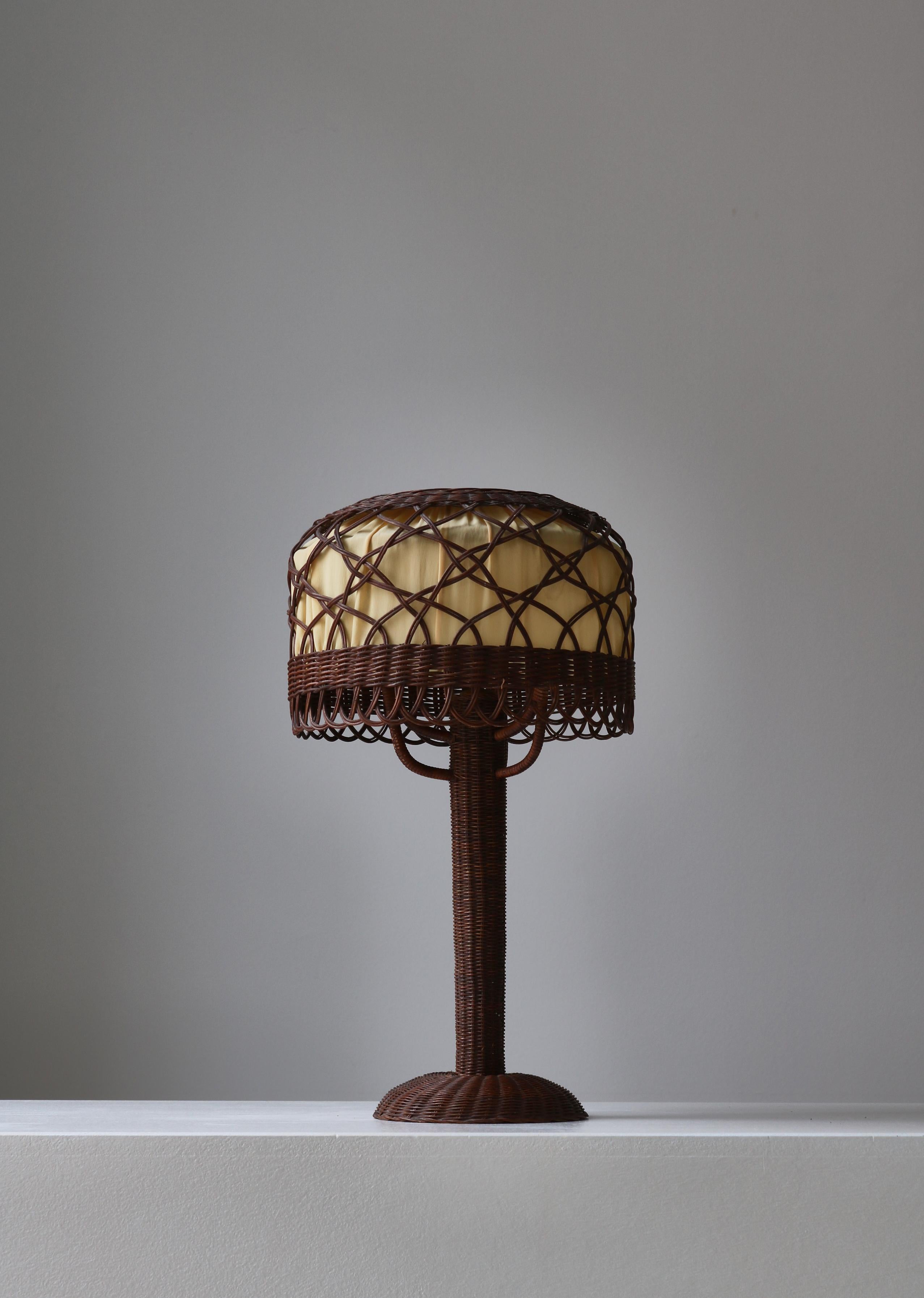 Splendida lampada da tavolo in stile Art Nouveau prodotta da Lund & Lawerentz, Copenaghen negli anni Trenta. La lampada è realizzata in rattan e conserva il paralume interno originale in tessuto beige. Lampada molto rara con una bellissima