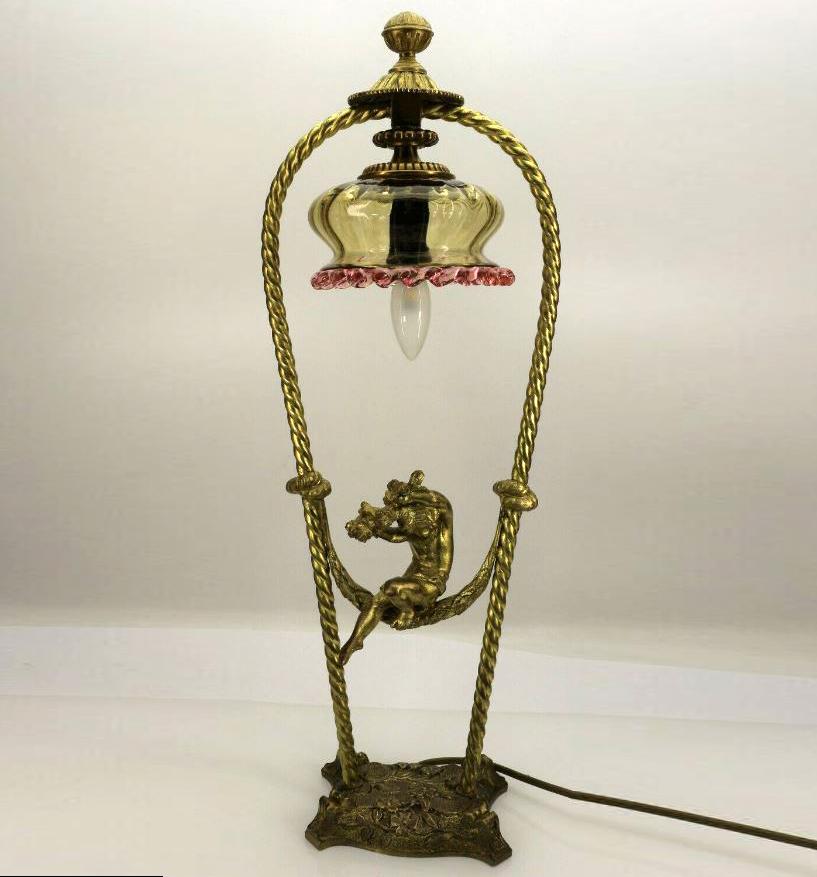 Art Nouveau table lamp putto on swing. Art Nouveau table lamp with glass shade and a playful appearance.
The lamp is rich pale gold coated. Production-related sharp edges on the frill edge (sharp tear-off)
Measures: Height 52 cm, diameter Ø 12