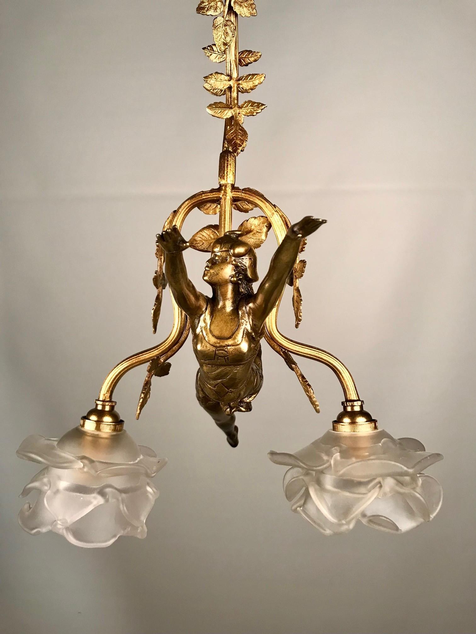 This is a fine example of Art Nouveau creativity in a two light figural pendant, chandelier. The gilt bronze figure is of a young women, (of course, what else?) apparently flying through the air, arms outstretched, legs in a kicking motion. She is