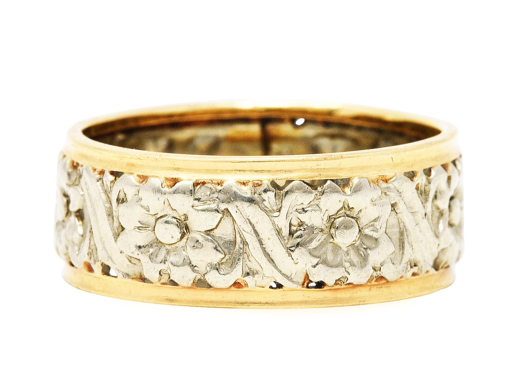 Band style ring with stylized floral detailing fully around 

Featuring a white gold mid-section with repoussè scrolling flowers

Flanked by ridged gold banding

Tested as 14 karat gold 

Circa: 1905

Ring size: 8 and not sizable 

Measures 8.0 mm
