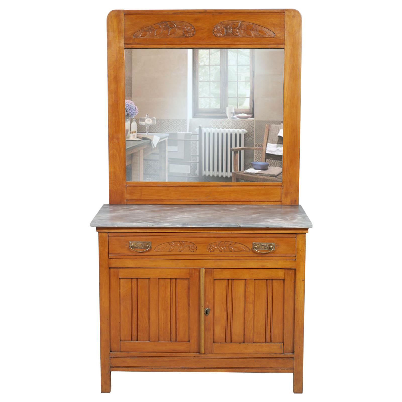 Early 20th century vanity cabinet Art Nouveau in hand carved solid cherrywood with bevelled mirror and marble top. Handles in burnished brass
All solid wood, restored and polished to wax

Cabinet suitable for a modern bathroom with the addition of a