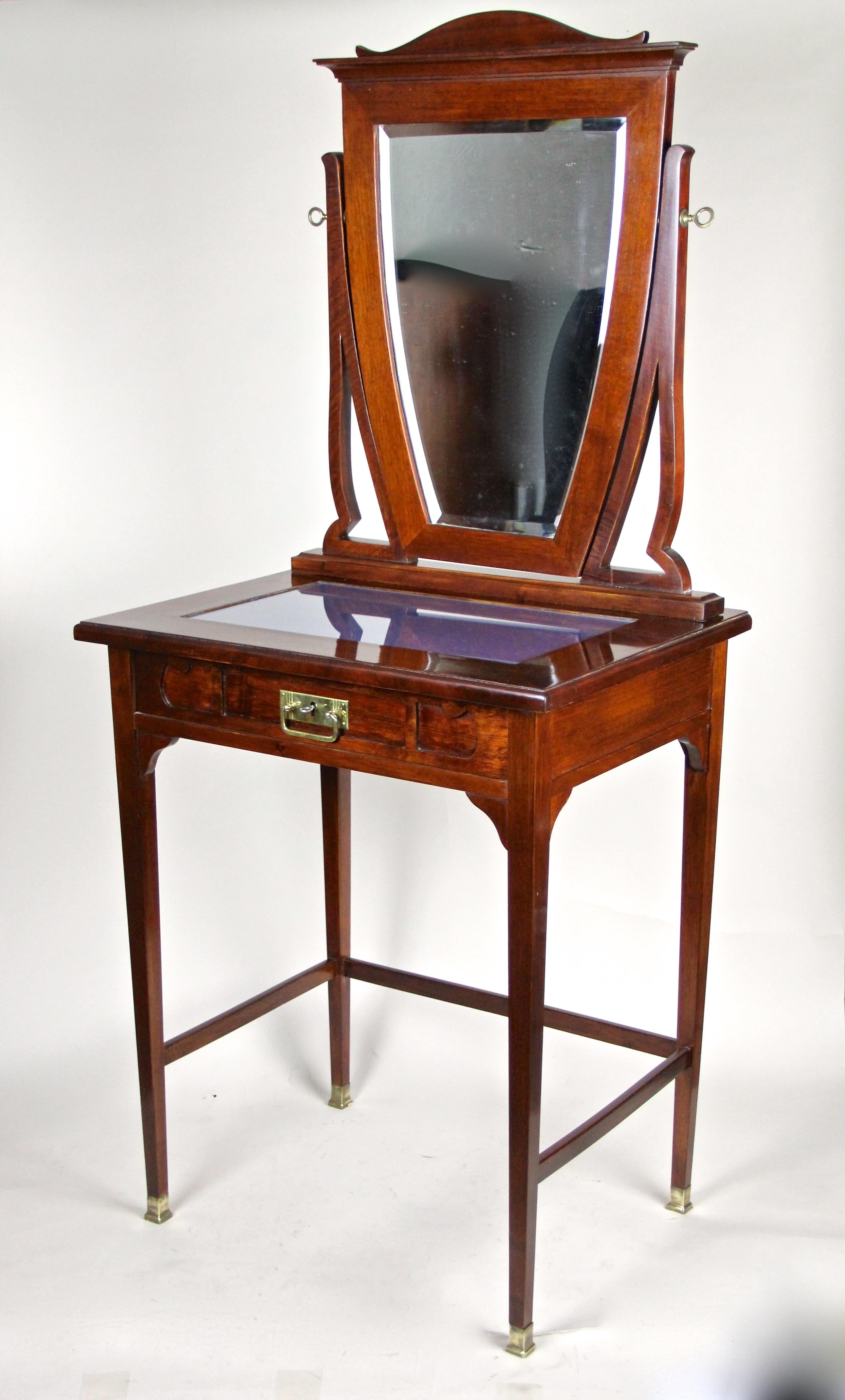 Fantastic Art Nouveau vanity table with swivel mounted mirror, made of beechwood and trimmed to a dark nut wood/ mahogany look. Elaborately processed in Austria circa early period of 1910, this incredibly charming vanity table covers one lockable