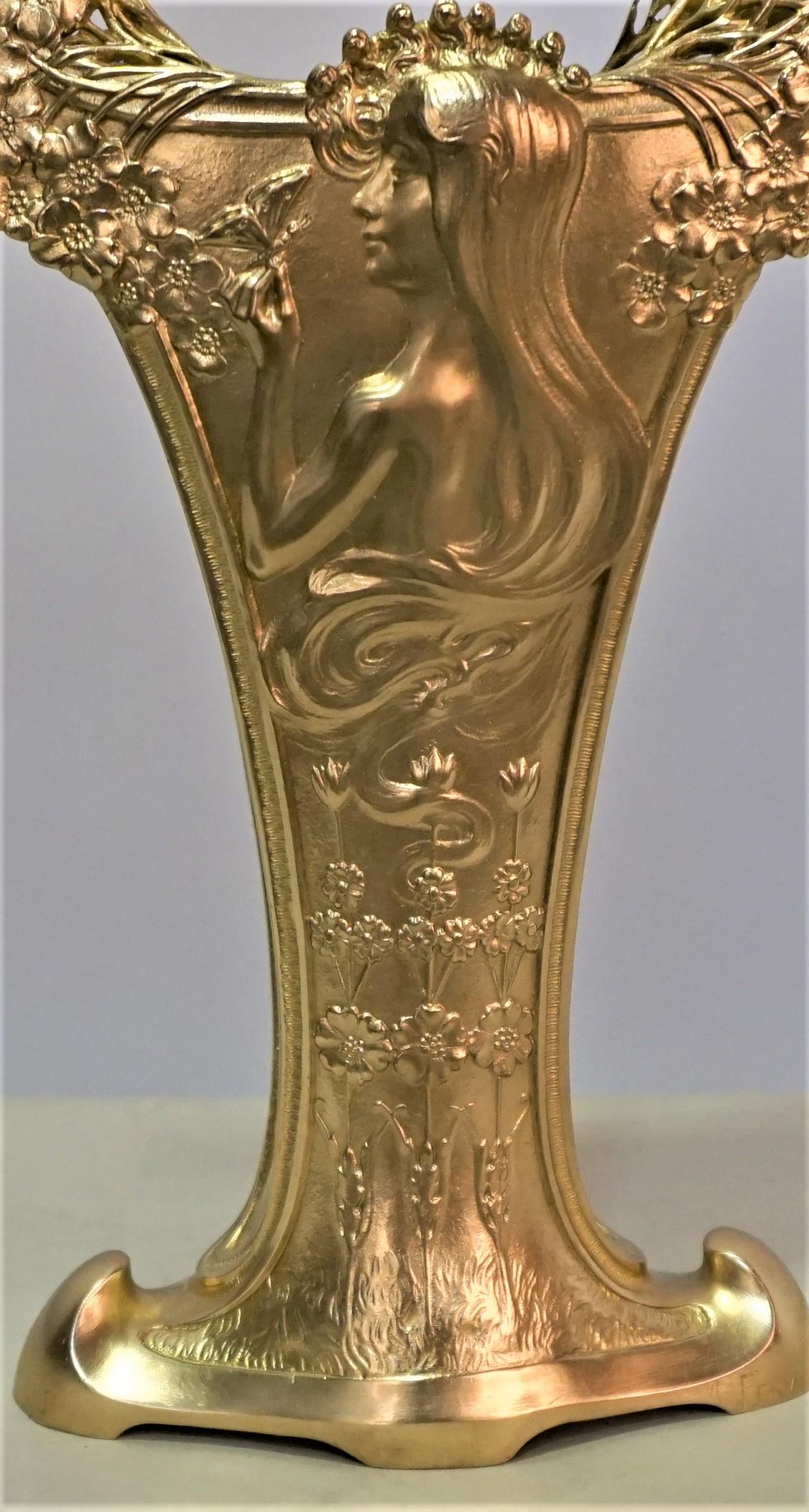 Vase avec relief de jeune fille entourée de fleurs tenant un papillon au bout de son doigt.