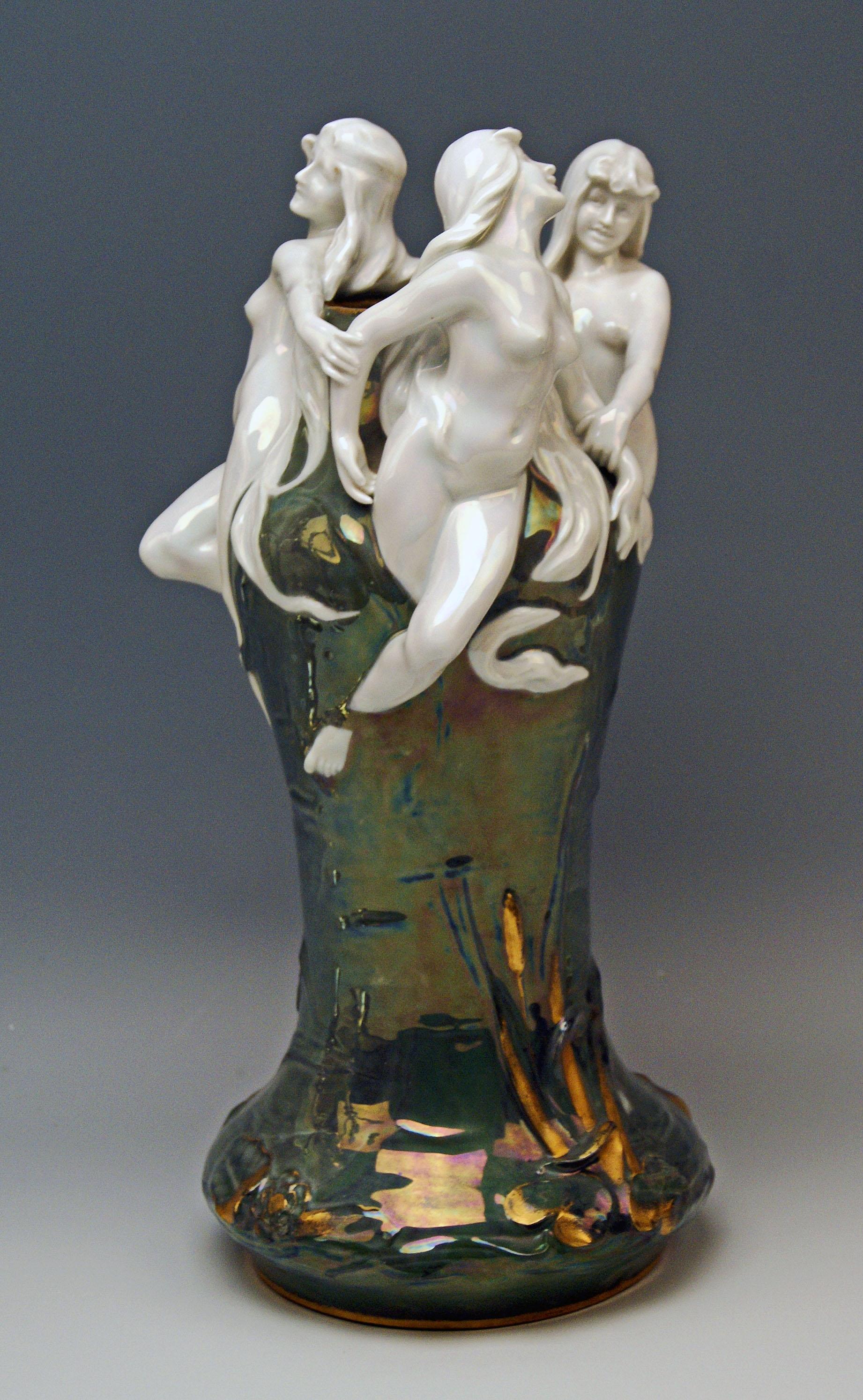 Gorgeous Art Nouveau vase made of porcelain / greyish-green shaded / glazed / partially golden shaded.
It is a stalky vase with widened area below and round mouth edged by stunningly sculptured white-shaded figurines: These are long-haired smiling