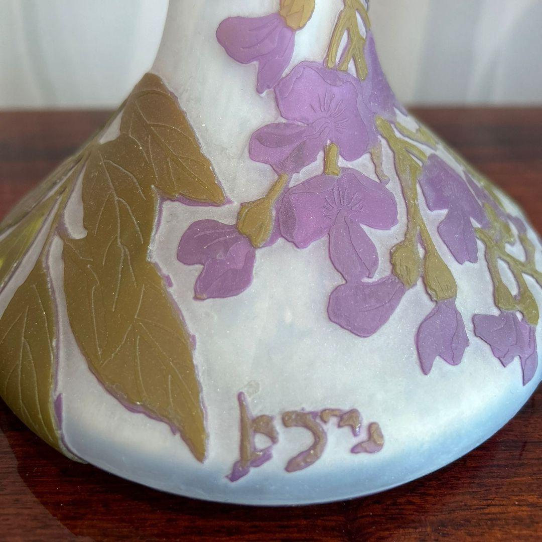 I vasi Legras, risalenti al 1900 circa, sono caratterizzati da vetro bianco sovrapposto a viola e verde, inciso con delicati motivi di glicine. Firmati dal rinomato vetraio francese Legras, questi vasi, alti 56 e 57,5 cm, esemplificano lo stile Art