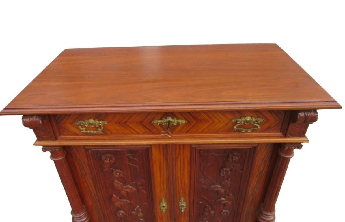An Art Nouveau chest of drawers manufactured, circa 1890. The body is made of oakwood and has walnut veneer columns held in solid walnut. A robust furniture without any worm damages. The doors are engraved by beautifully carved flower-tendrils, with