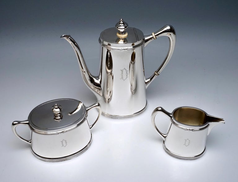 Elegant, simple, 4-part silver core consisting of a coffee pot, milk jug, sugar bowl and tray. Vessels with an oval basic shape and smooth walls, narrowing slightly conically towards the top, with profiled ribbons on the lower edge and on top, here