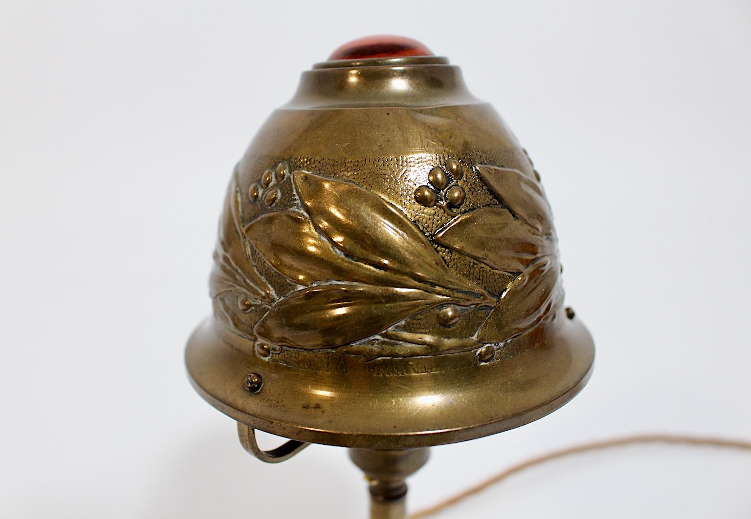 Art Nouveau vintage dome table lamp or bedside lamp from brass and glass decor stone circa 1910 France.
A stunning table lamp from brass with an embossed dome shade and a decor stone in amber color.
The dome shade shows embossed leaves, while the