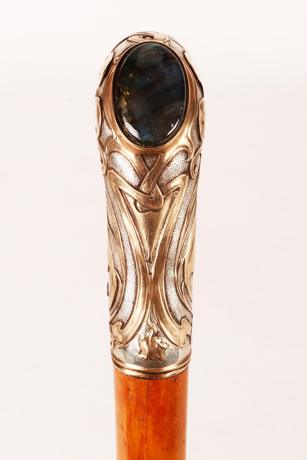 Art Nouveau walking stick: L-shaped knob, made of 800/1000 silver metal, engraved and low-relief workmanship with Liberty and vegetal motifs, partially gilded. Central stone, a cabochon cut labradorite. Rattan wood cane. Brass and iron ferrule.