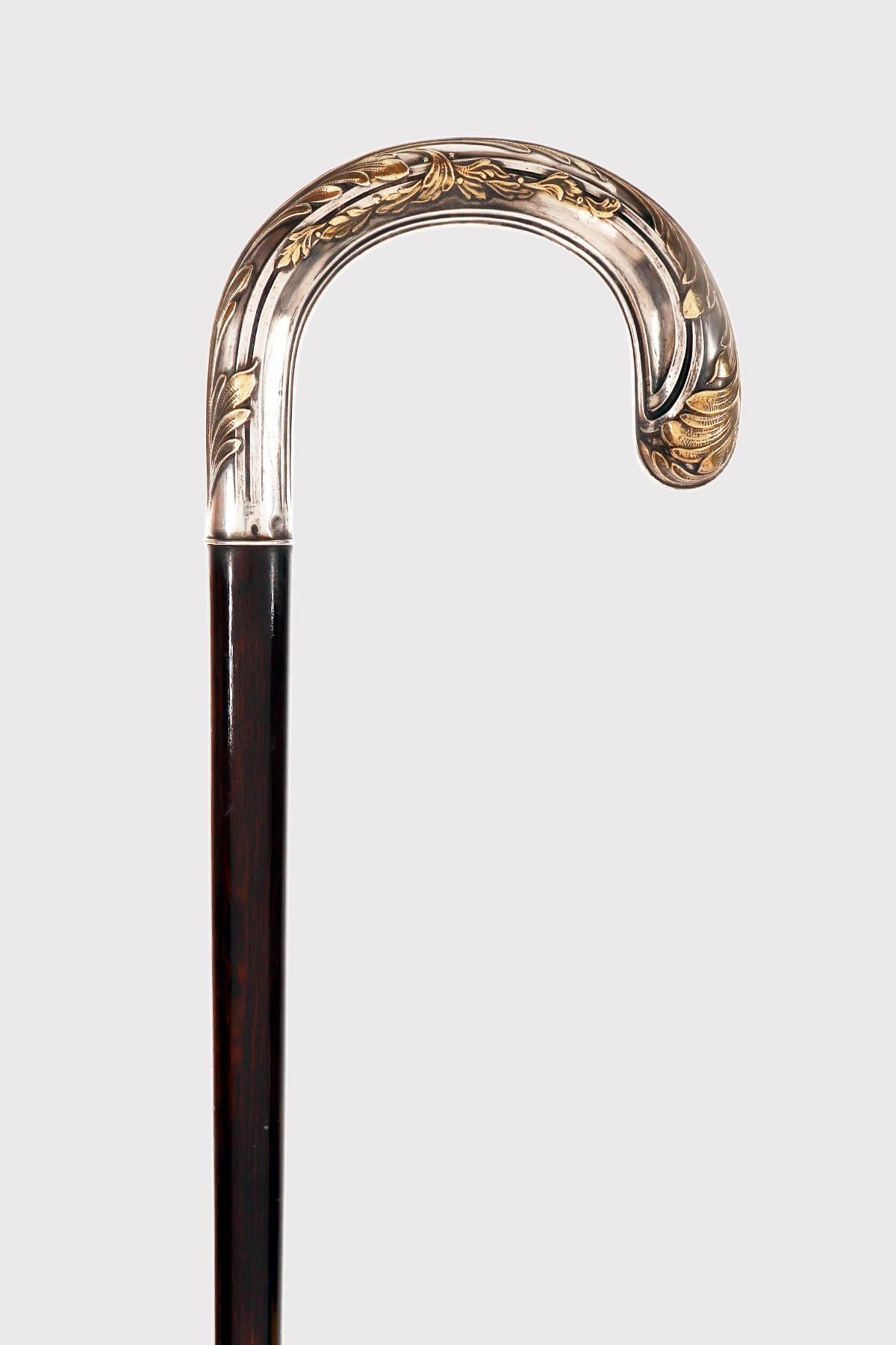 Bastone da passeggio in stile Art Nouveau: pomello curvo in argento dorato, raffigurante foglie in rilievo. Albero in legno di serpente. Ghiera in ottone. Francia, circa 1900.
