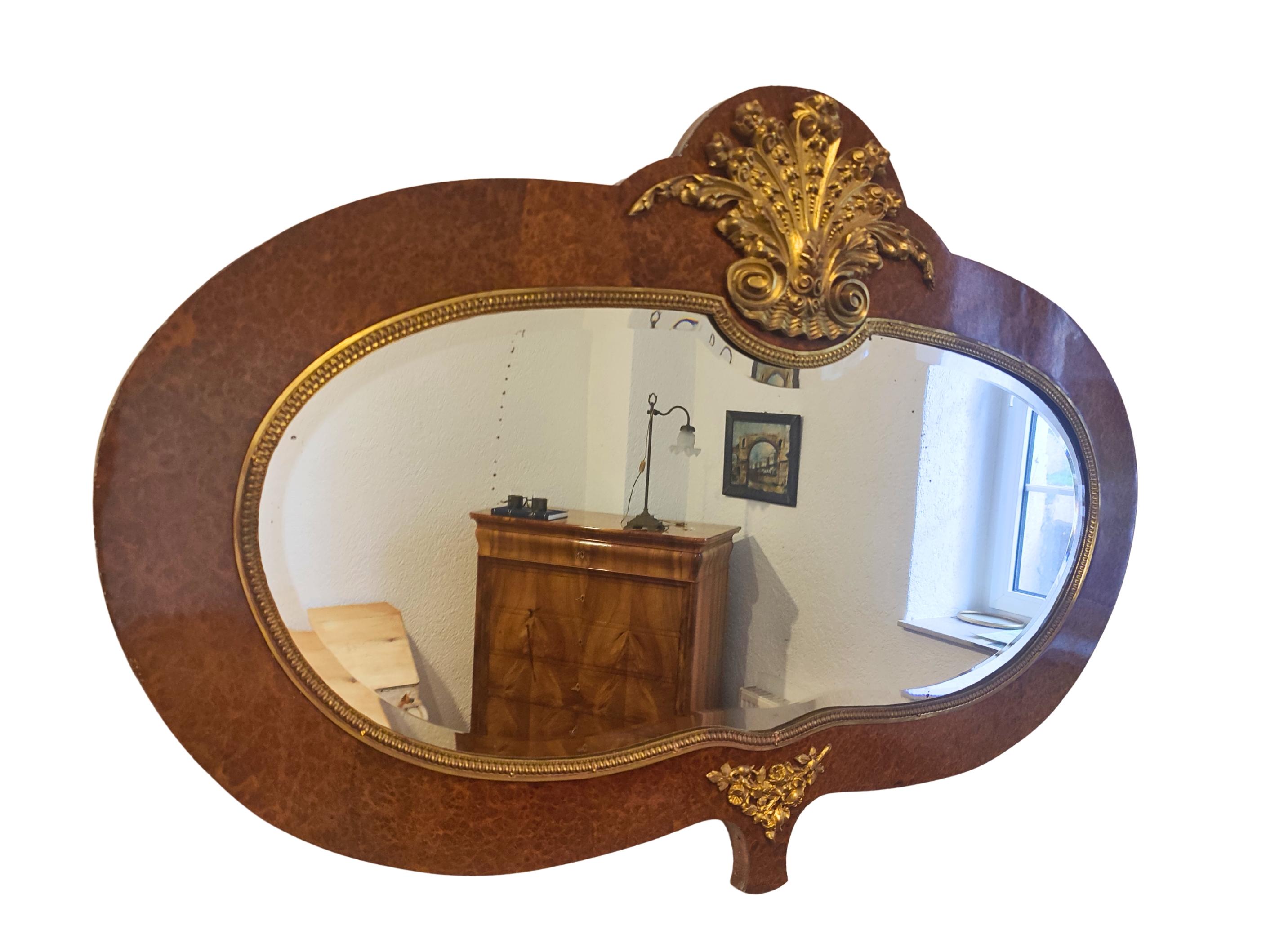 Cet élégant miroir mural Art nouveau date d'environ 1900 et a vraisemblablement été fabriqué en France. Le cadre est plaqué en érable piqué magnifiquement figuré, avec un ton chaud et doré et un contour doux et organique typique de l'époque. La