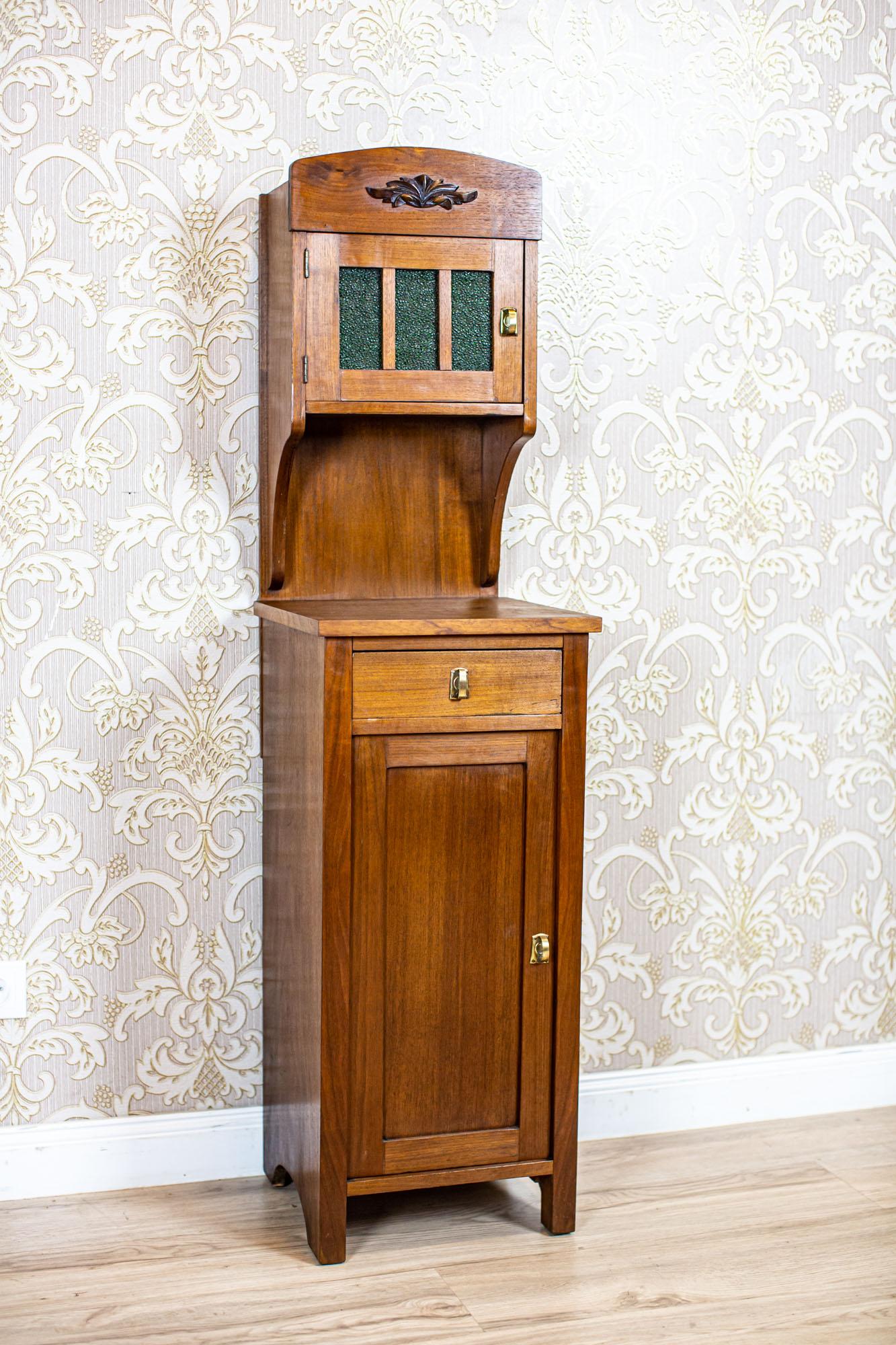 Art Nouveau Walnut Nightstand from the Early 20th Century with Glass Pane

A walnut piece of furniture composed of a single-leaf base and an add-on unit fixed to the rear wall, with original glass panes in the door leaf.
The escutcheons and ball